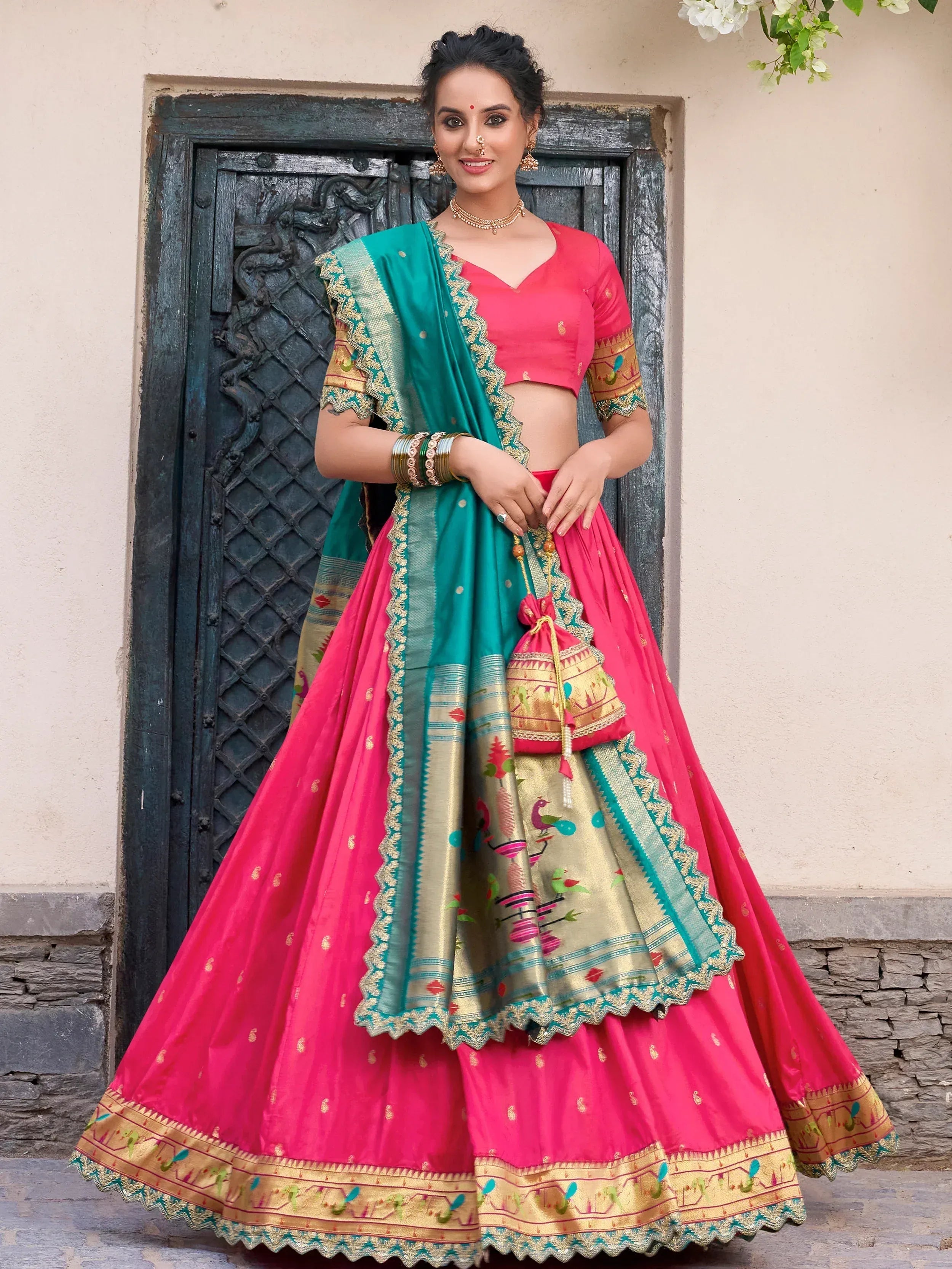Vibrant pink and teal lehenga choli with intricate embroidery and gold detailing, perfect for festive occasions.