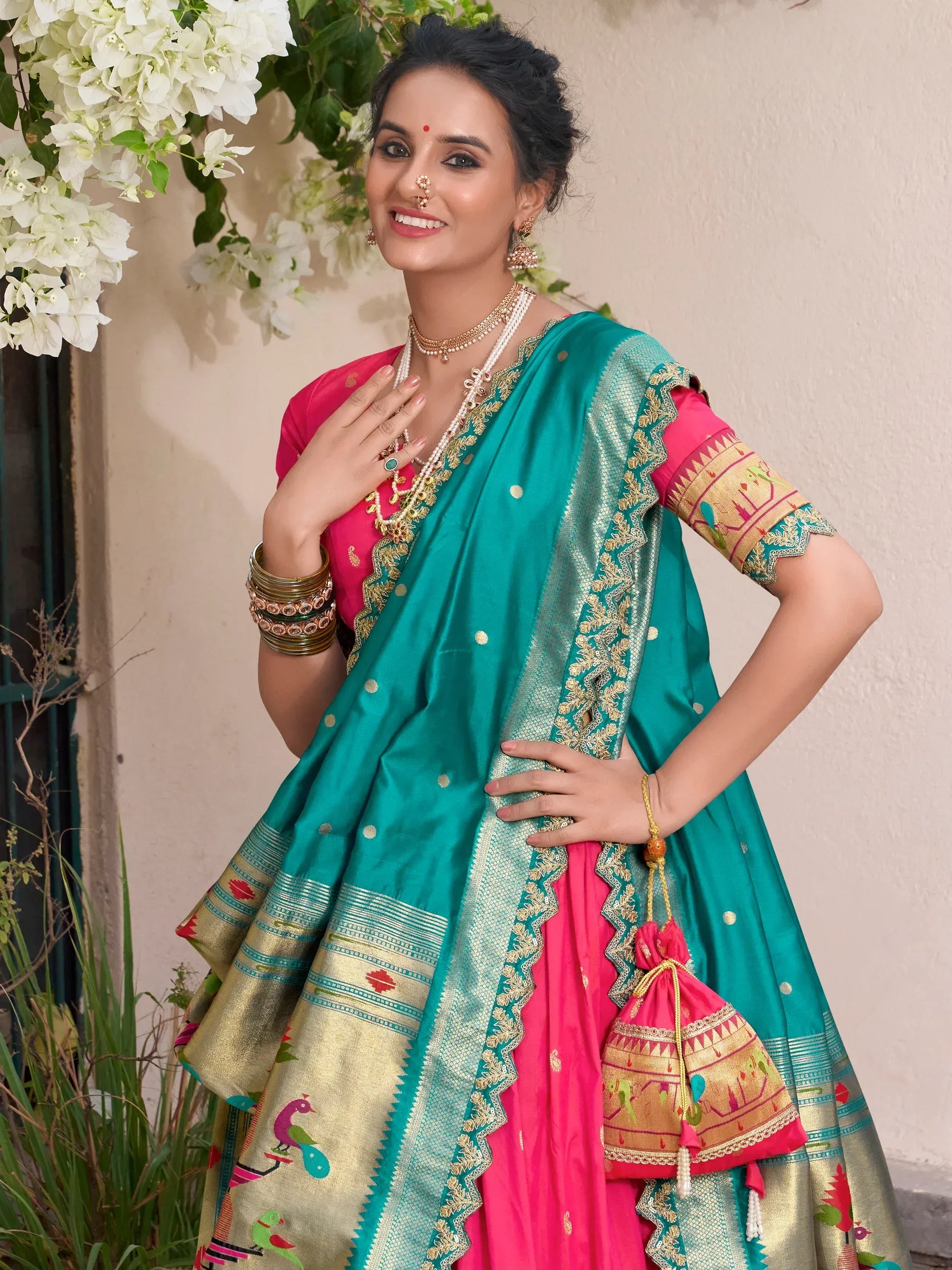 Teal and pink ethnic saree with gold embroidery and peacock motifs, styled with traditional jewelry