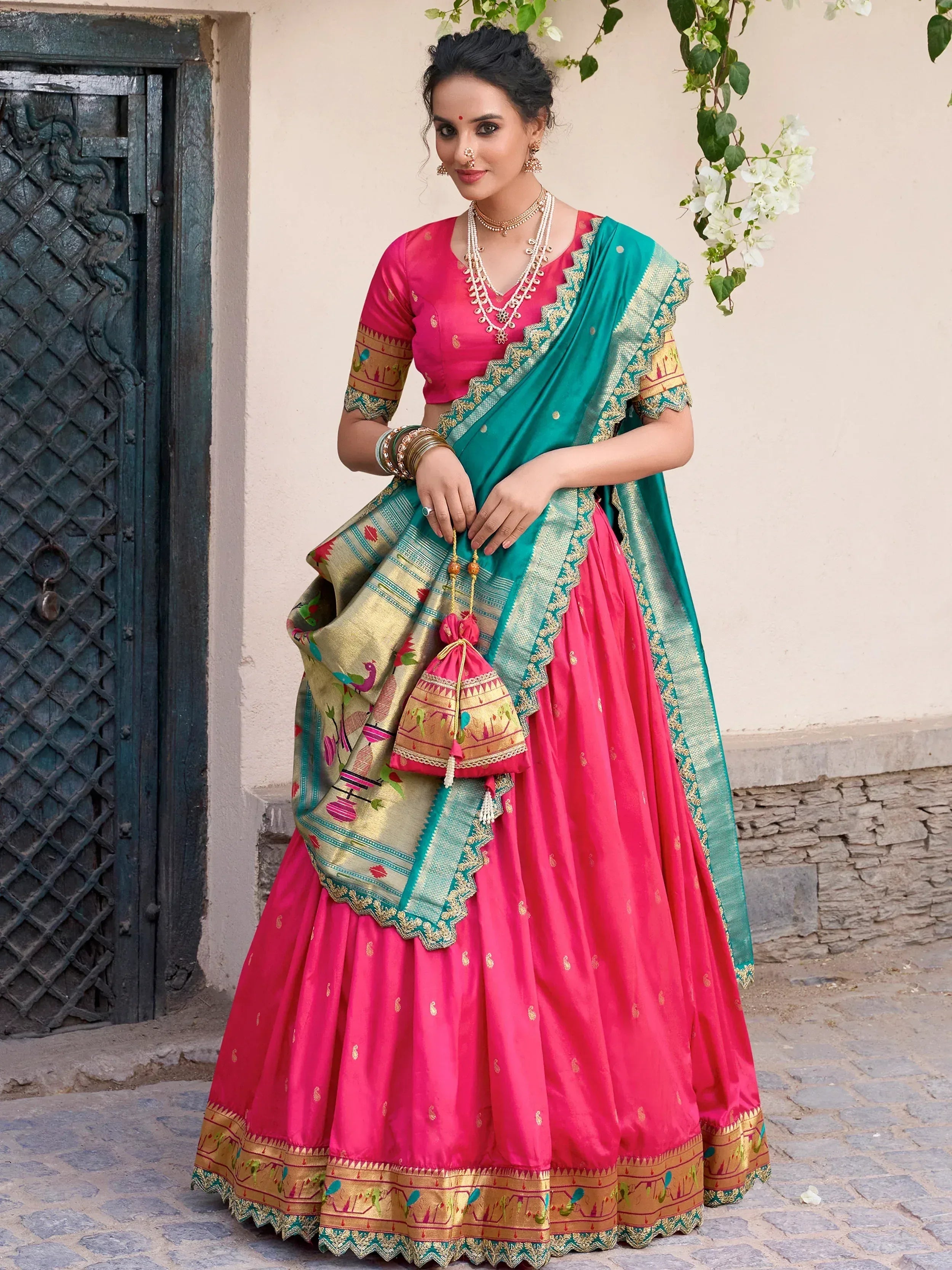Vibrant pink and teal designer lehenga choli with intricate embroidery and gold detailing, perfect for festive occasions.