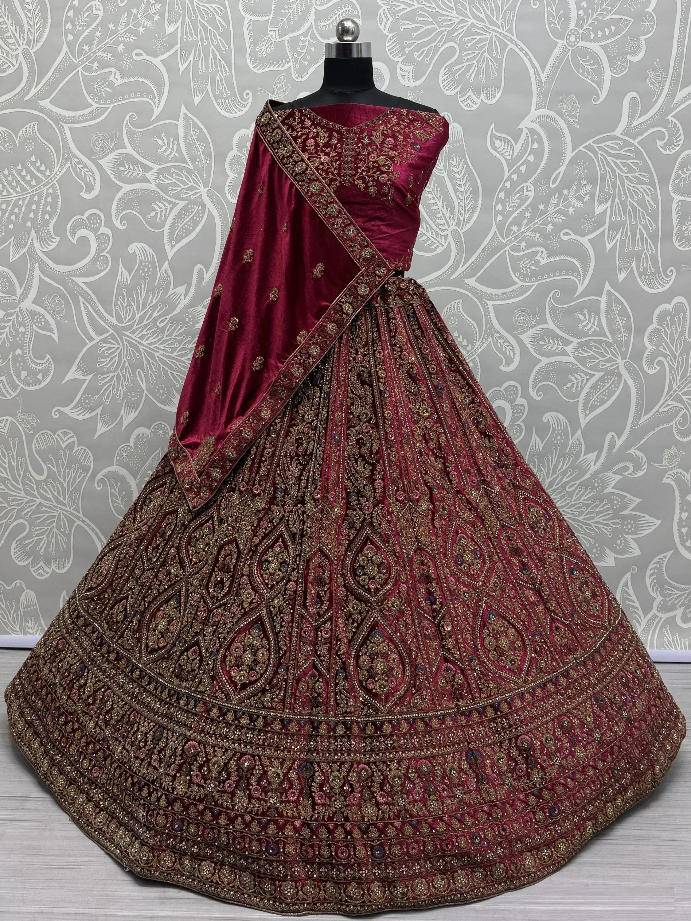 Maroon velvet lehenga choli with heavy gold embroidery, perfect for Indian weddings and festive occasions.
