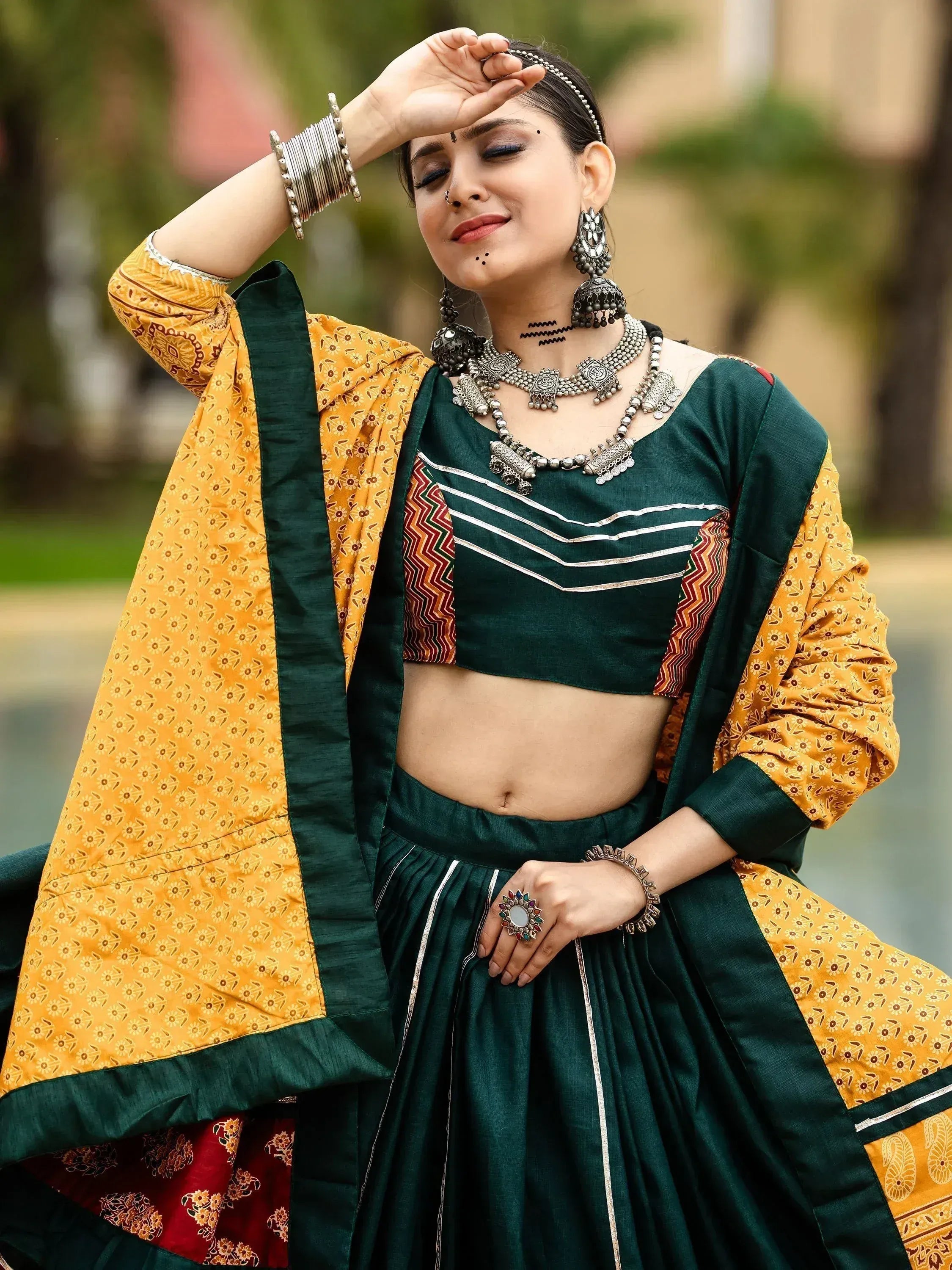 Green and yellow ethnic lehenga choli with silver jewelry, perfect for Indian weddings or festive occasions.