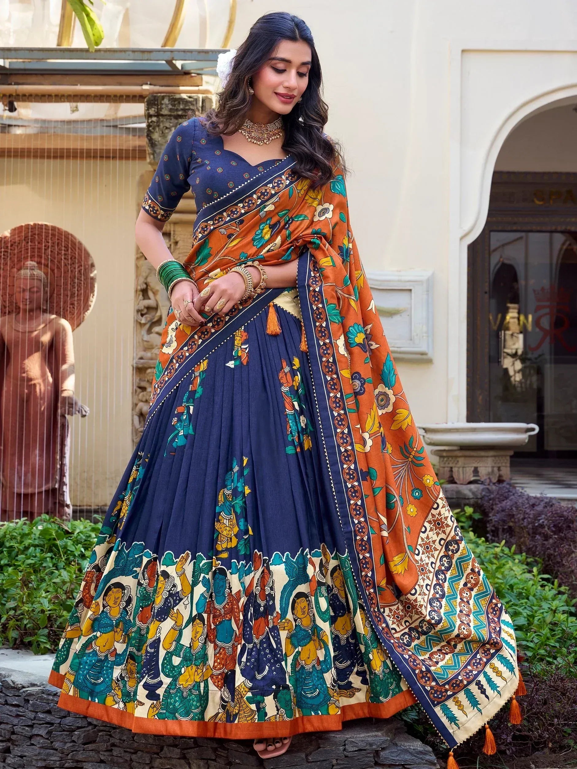 Woman in navy blue and orange printed lehenga choli with floral dupatta, ethnic Indian wear