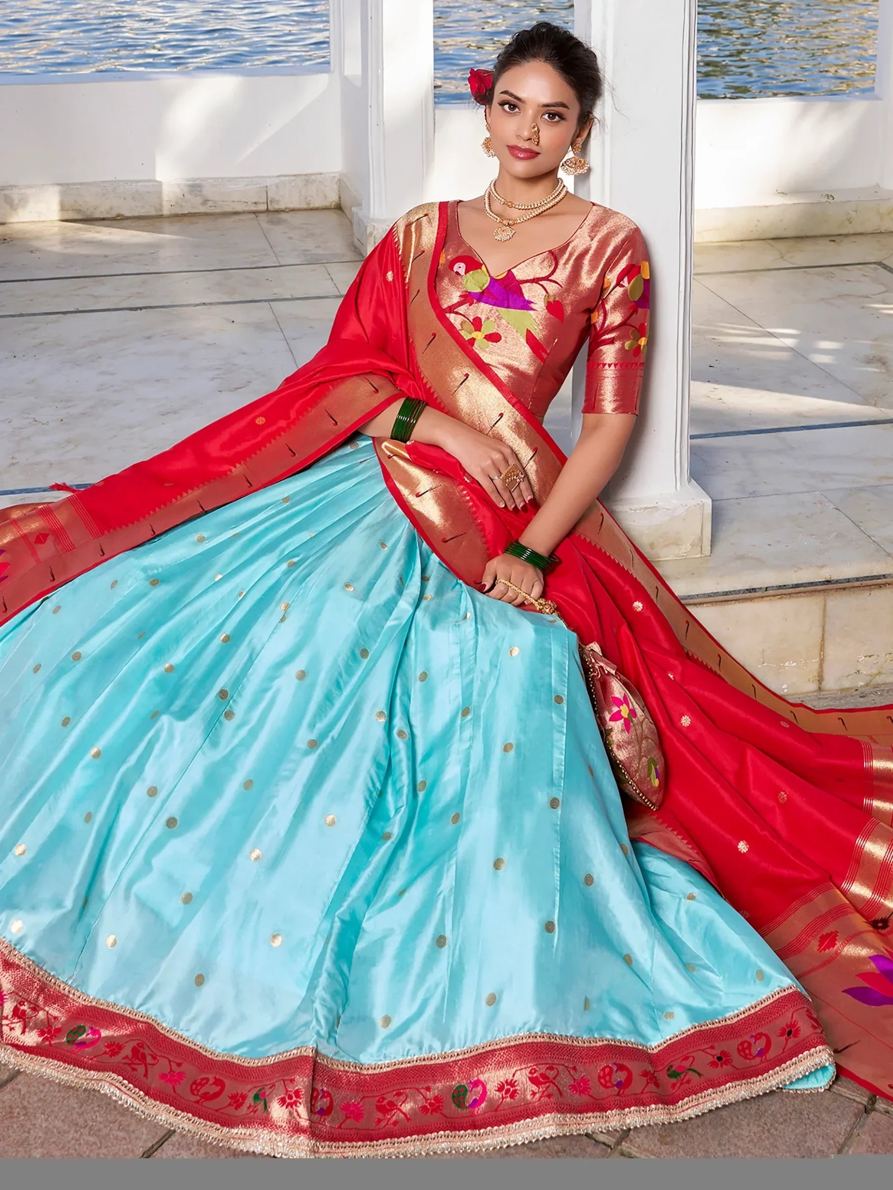 Woman in vibrant blue and red designer lehenga choli with bird embroidery, perfect for Indian ethnic occasions.