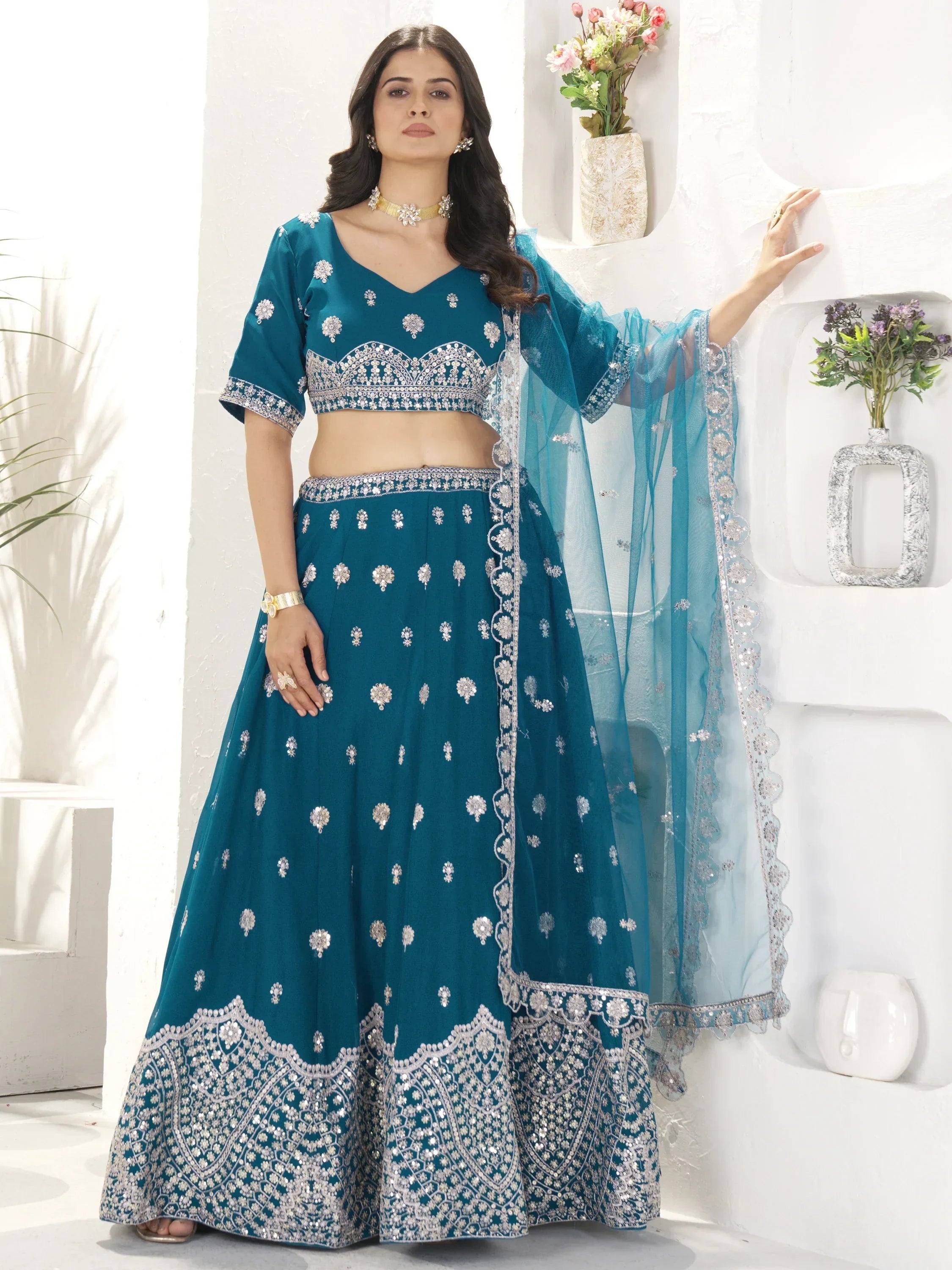 Teal blue designer lehenga choli with silver embroidery and sheer dupatta, perfect for Indian ethnic wear occasions.