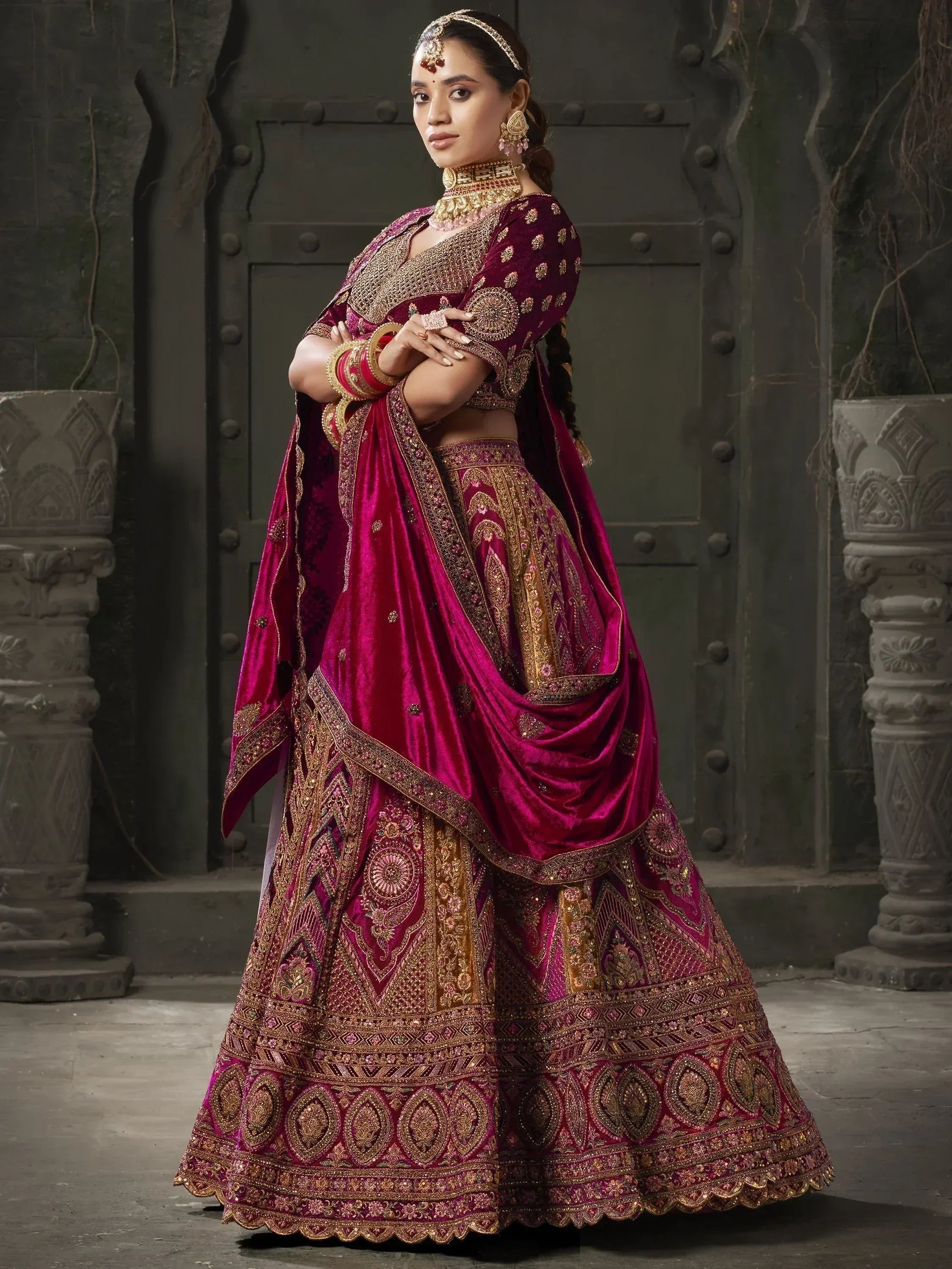 Luxury maroon velvet lehenga choli with gold embroidery, perfect for Indian weddings and festive occasions.