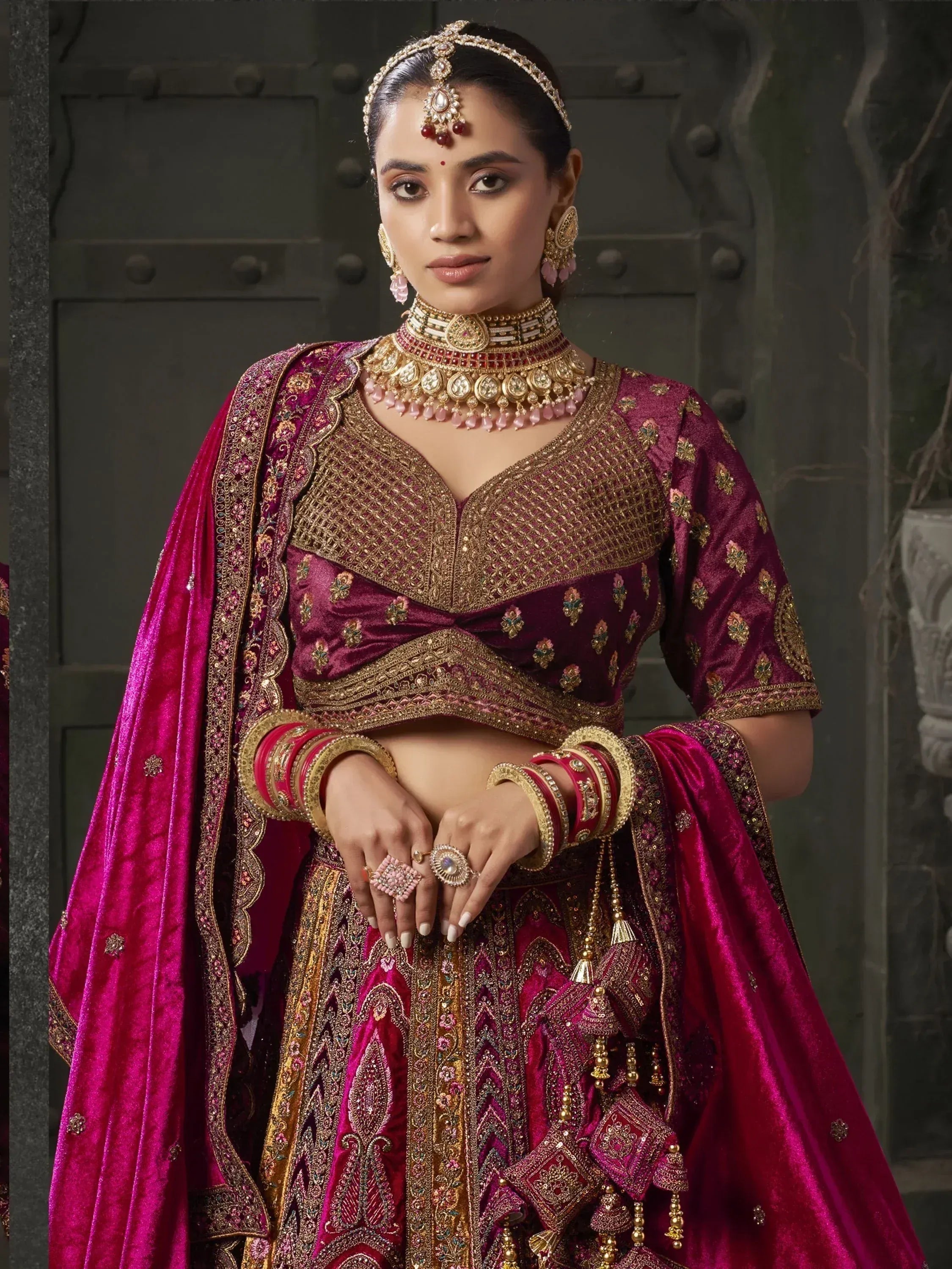 Elegant maroon velvet lehenga choli with gold embroidery, perfect for Indian weddings and festive occasions.