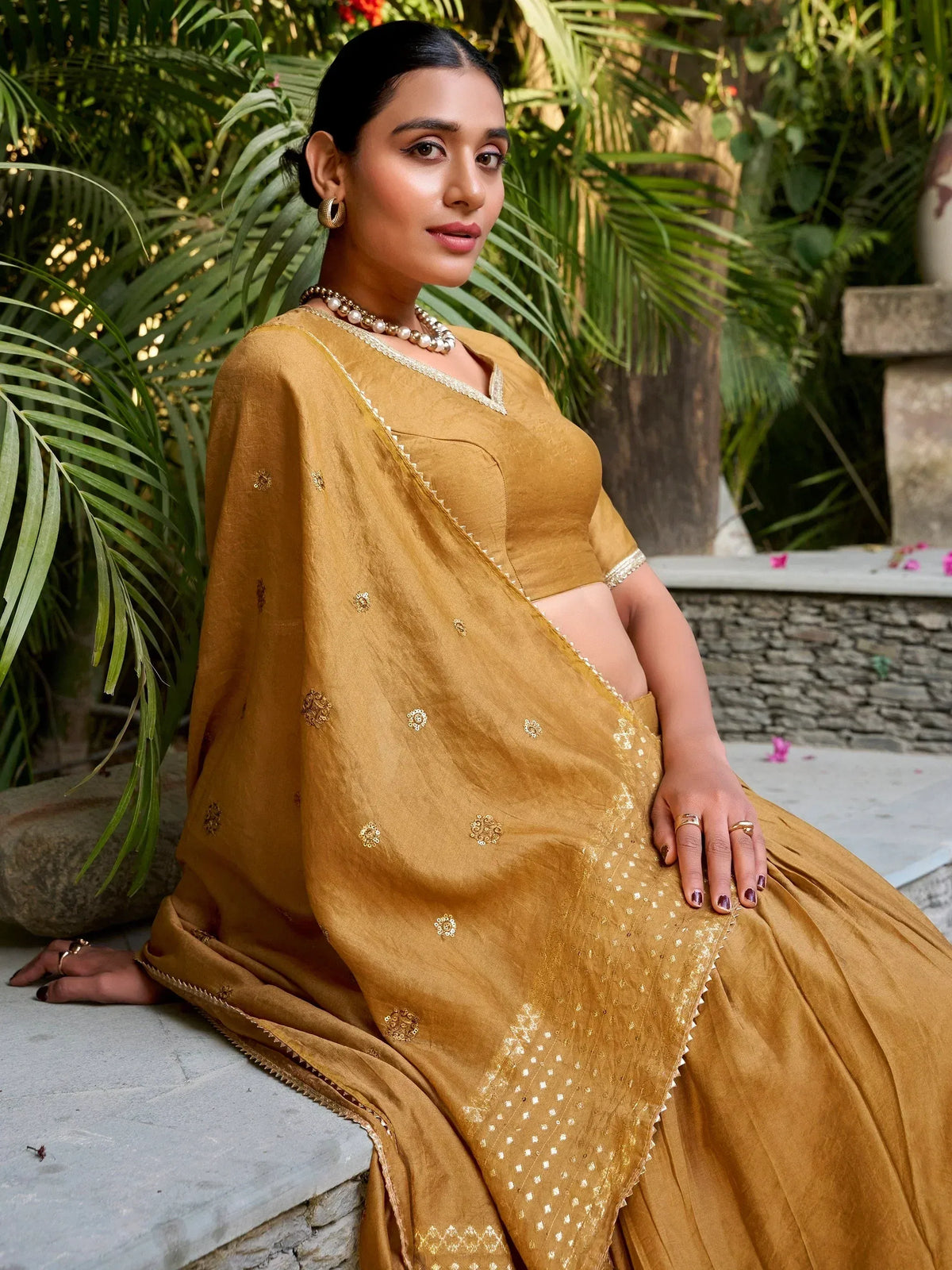 Mustard yellow ethnic saree with gold embroidery, styled with pearl jewelry for Indian occasions
