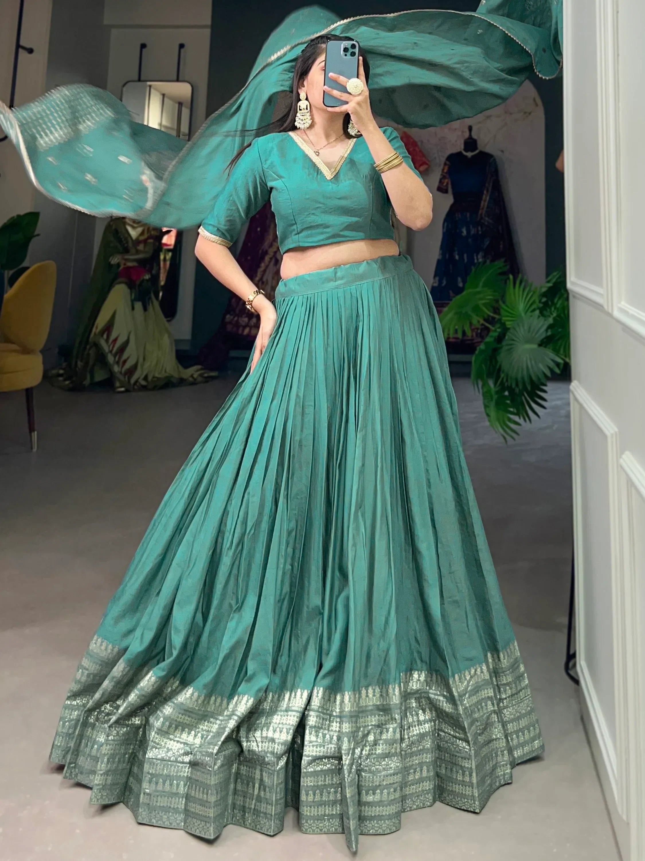 Teal green lehenga choli with gold trim, pleated skirt, and flowing dupatta for Indian ethnic wear