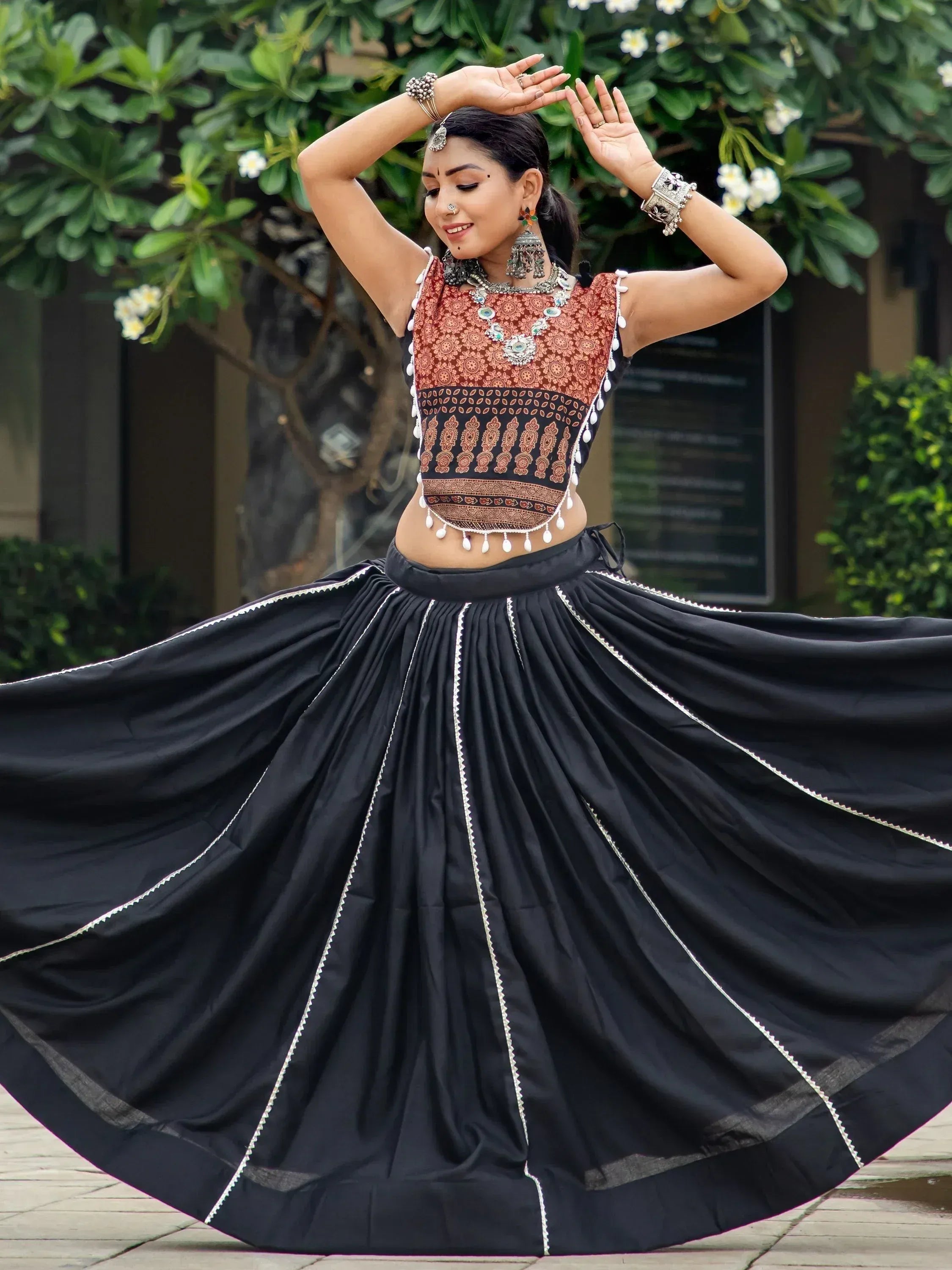 Woman dancing in black and red ethnic lehenga choli with intricate embroidery and silver jewelry