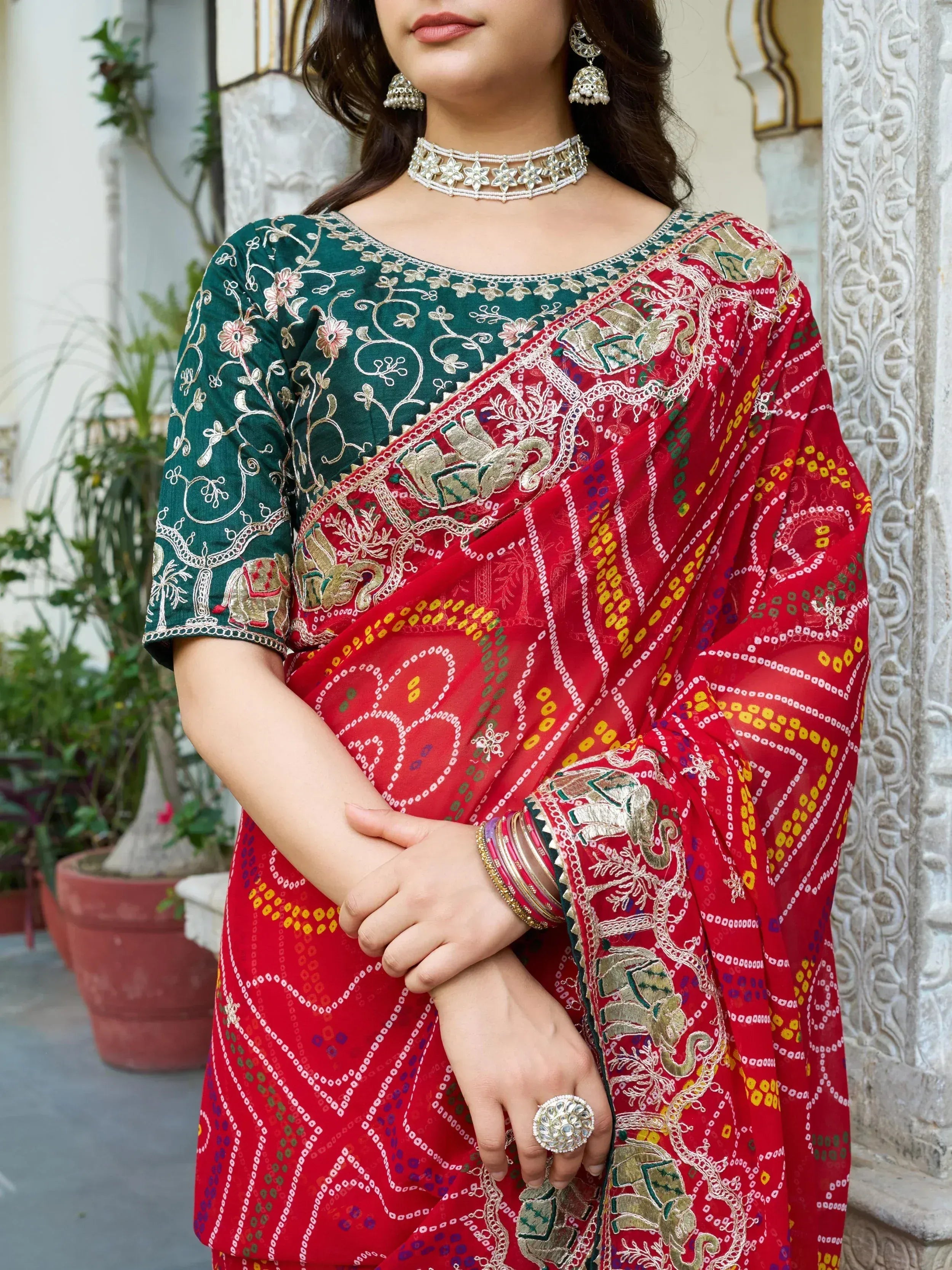 Red and green embroidered saree with elephant motifs, floral blouse, and traditional jewelry
