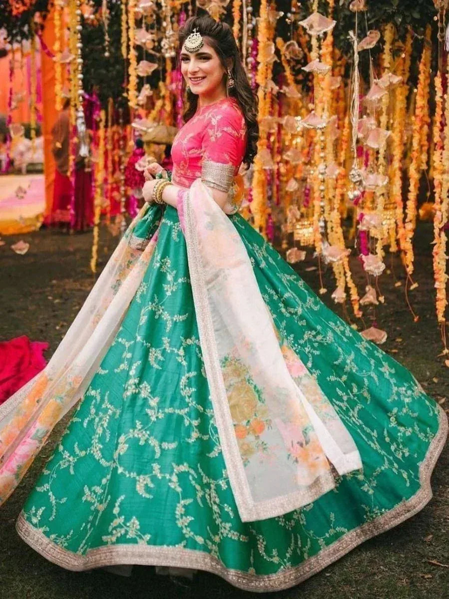 Woman in pink and green designer lehenga choli with floral dupatta, perfect for Indian weddings and festive occasions.