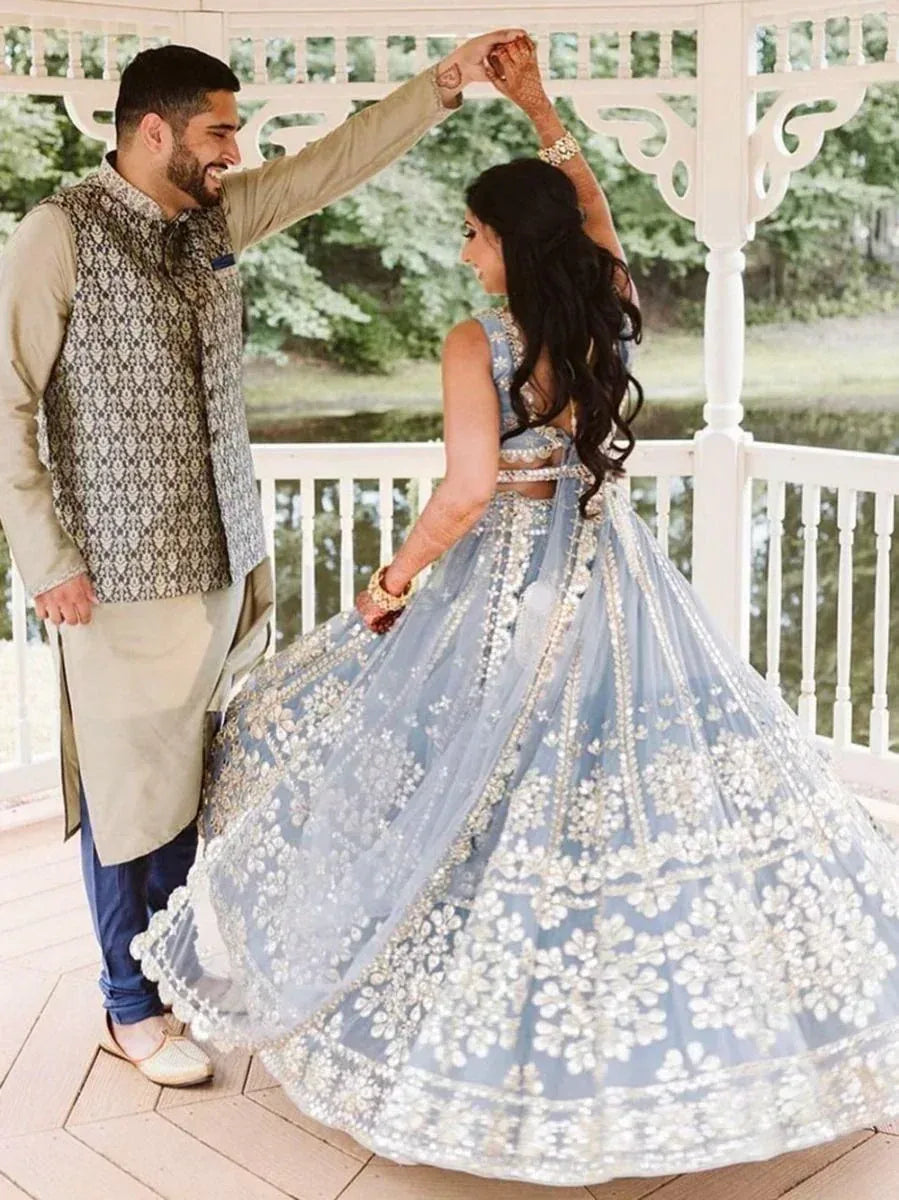 Elegant blue lehenga choli with floral embroidery, paired with men's kurta and vest for Indian wedding wear
