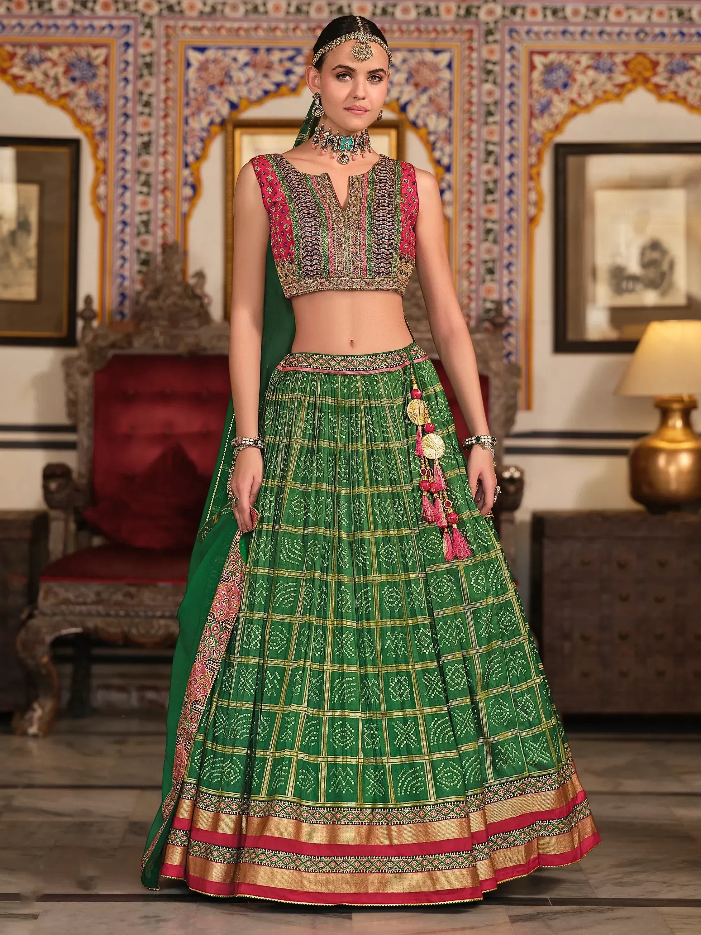 Green and pink embroidered lehenga choli with traditional Indian motifs and tassels, perfect for festive occasions.