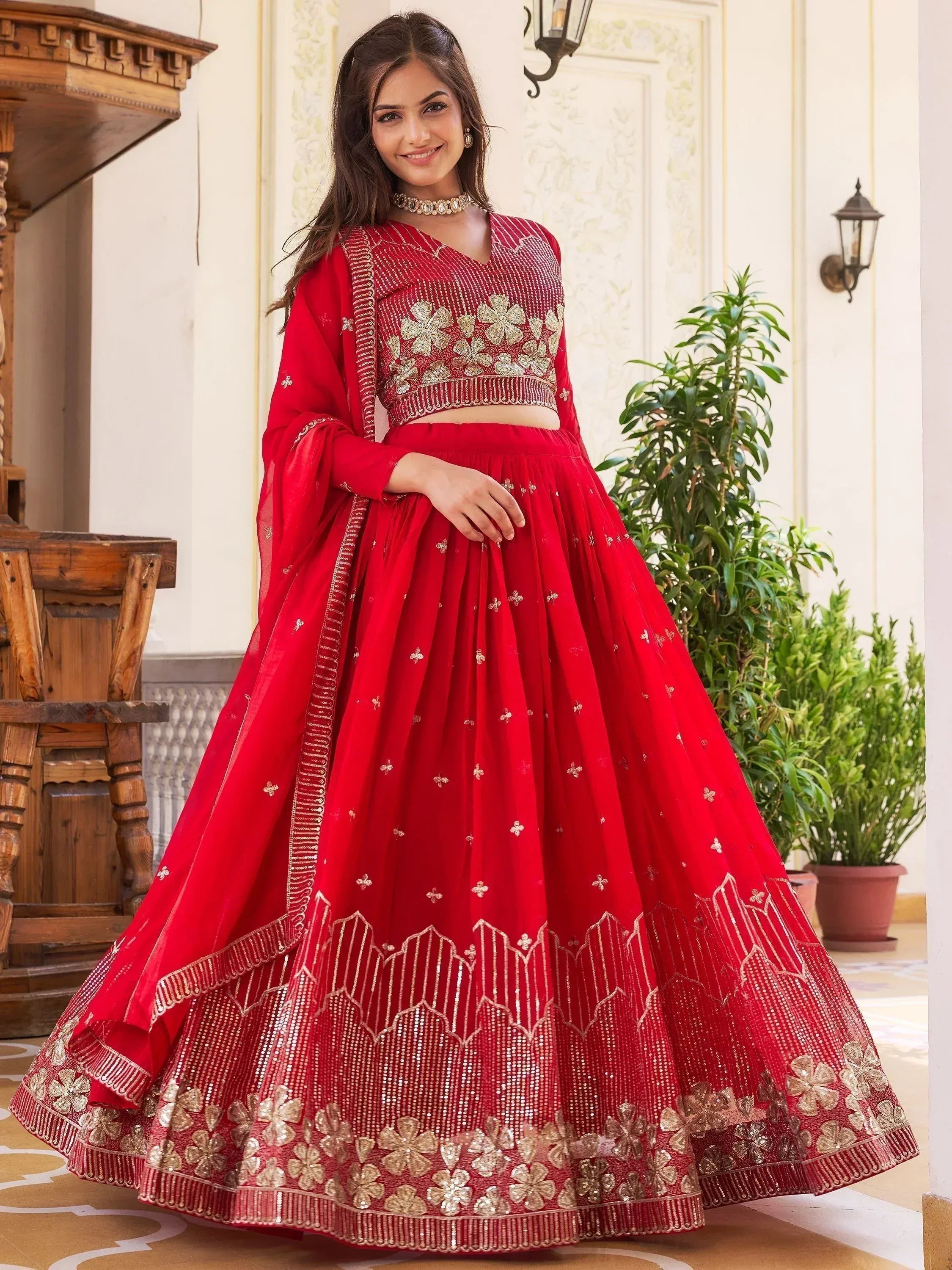 Red embroidered lehenga choli with gold floral work, perfect for Indian weddings and festive occasions.