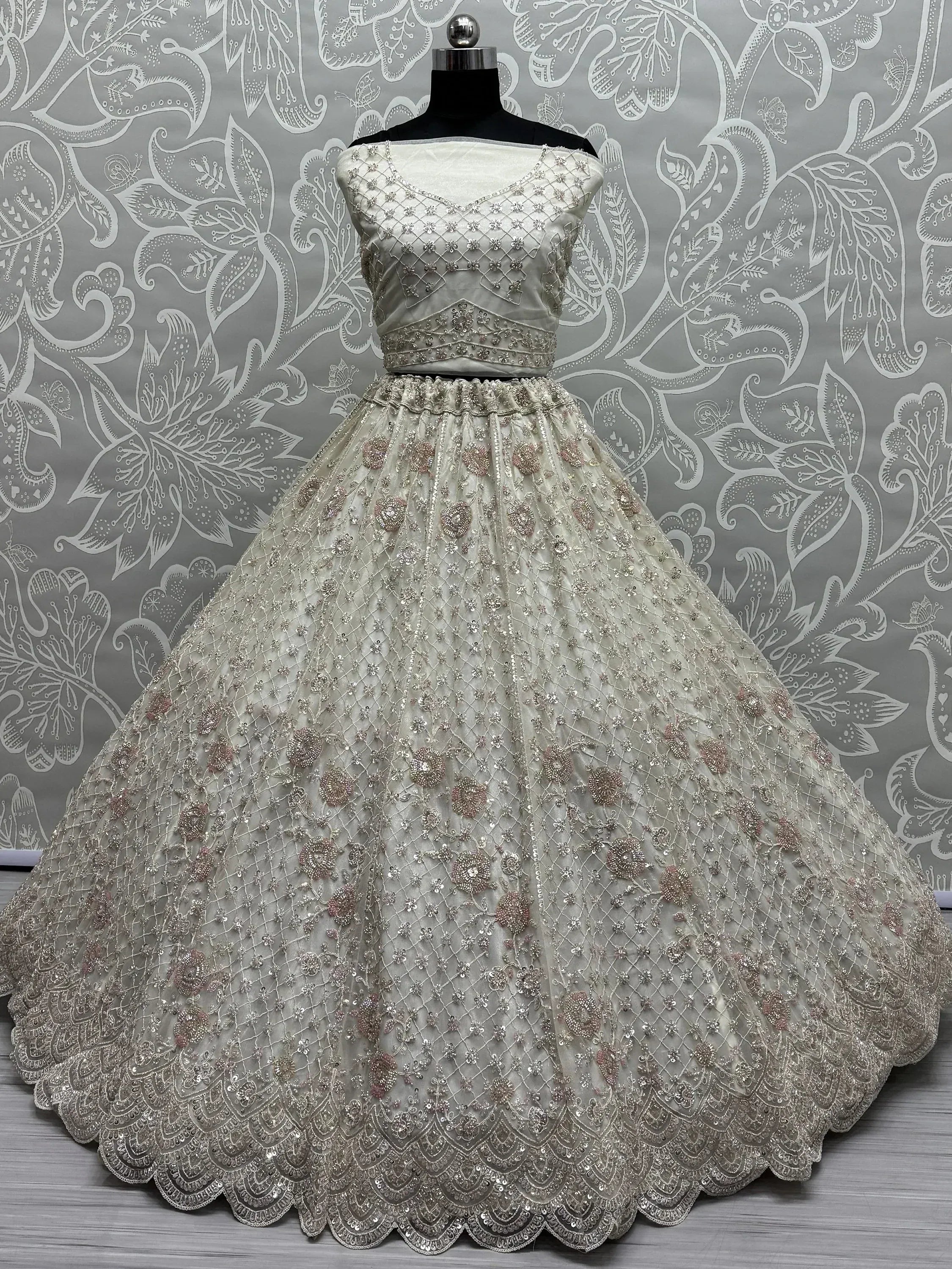 Elegant off-white designer lehenga choli with intricate floral embroidery and sequin work, perfect for weddings and festive occasions.