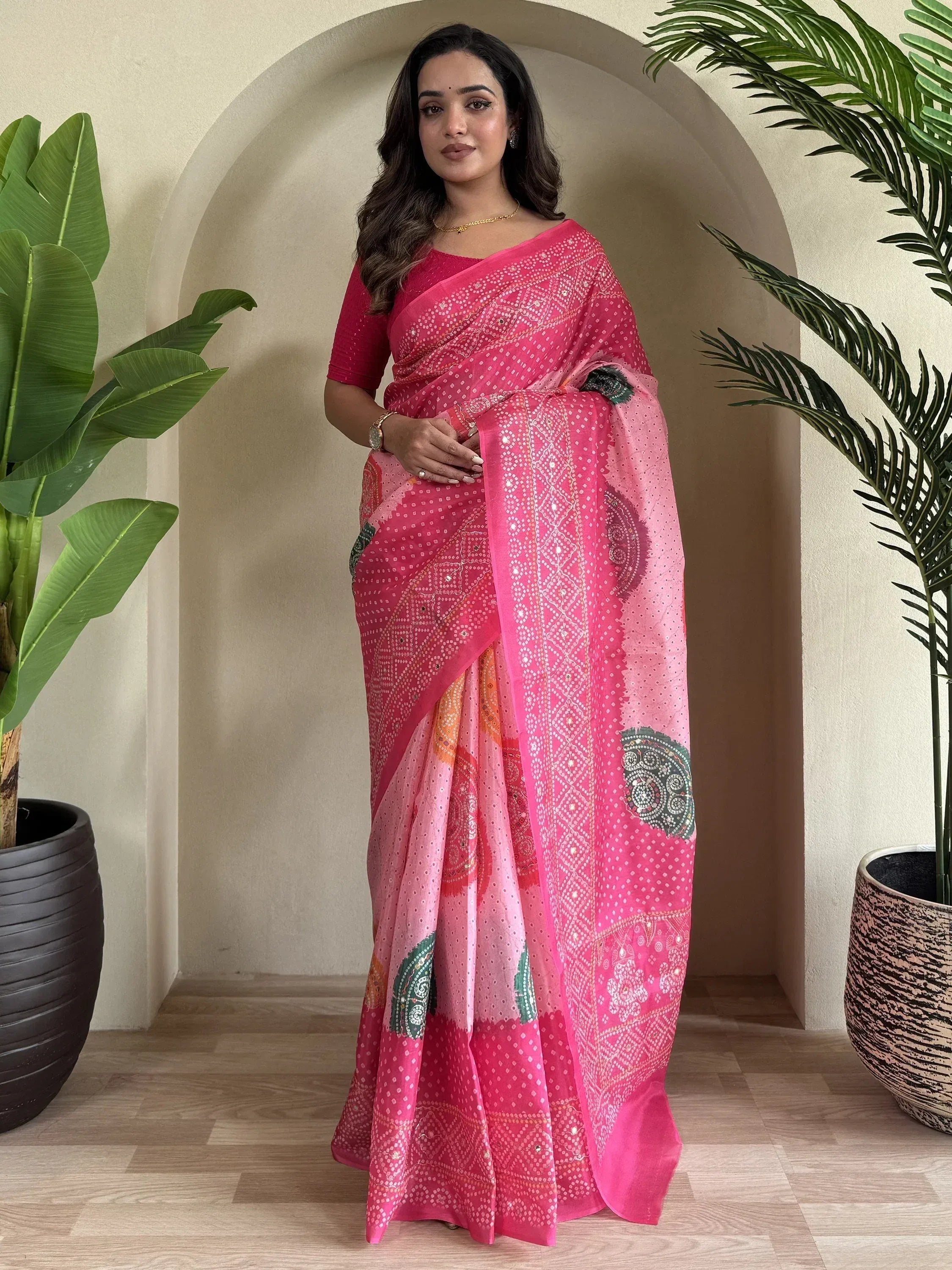 Woman in vibrant pink embroidered saree with mirror work, styled for ethnic occasions