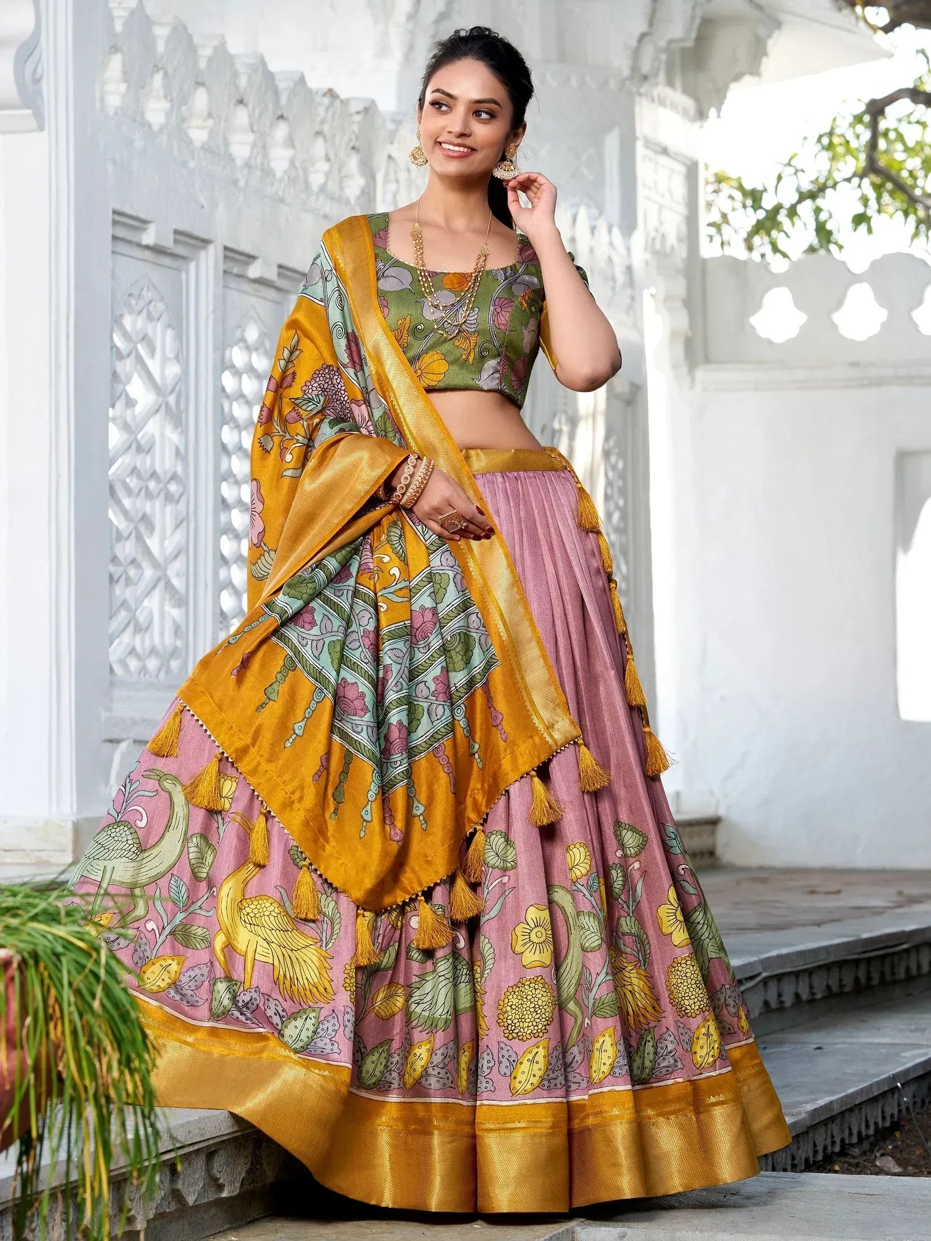 Woman in colorful floral lehenga choli with peacock print, gold border, and tassels, ideal for Indian ethnic wear.