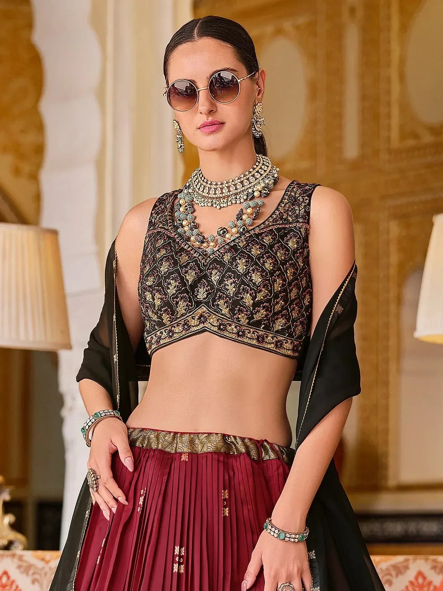 Black embroidered blouse with maroon pleated skirt, traditional Indian ethnic wear, paired with statement jewelry