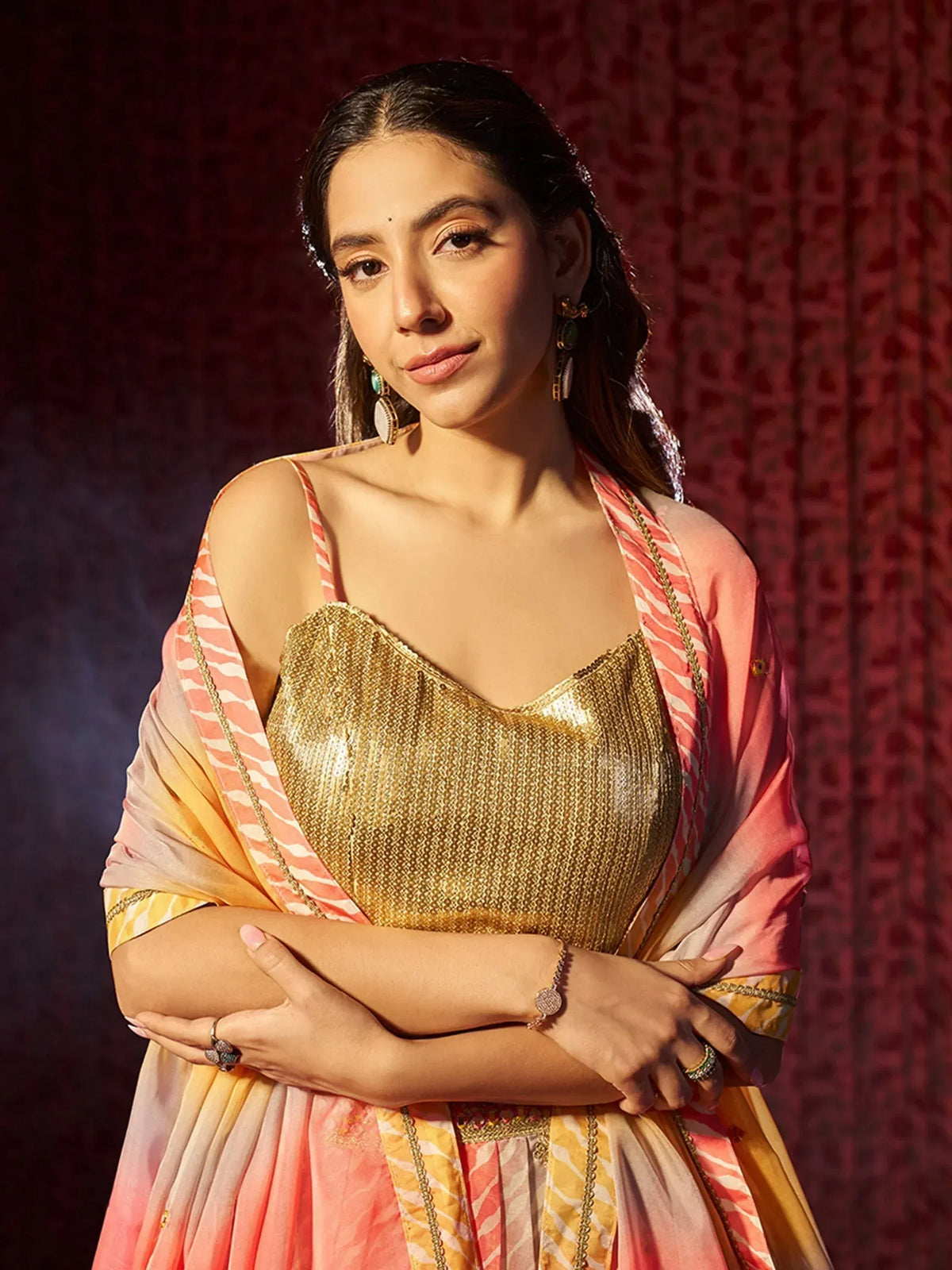 Woman in gold sequin top with pink and yellow striped dupatta, ethnic Indian wear