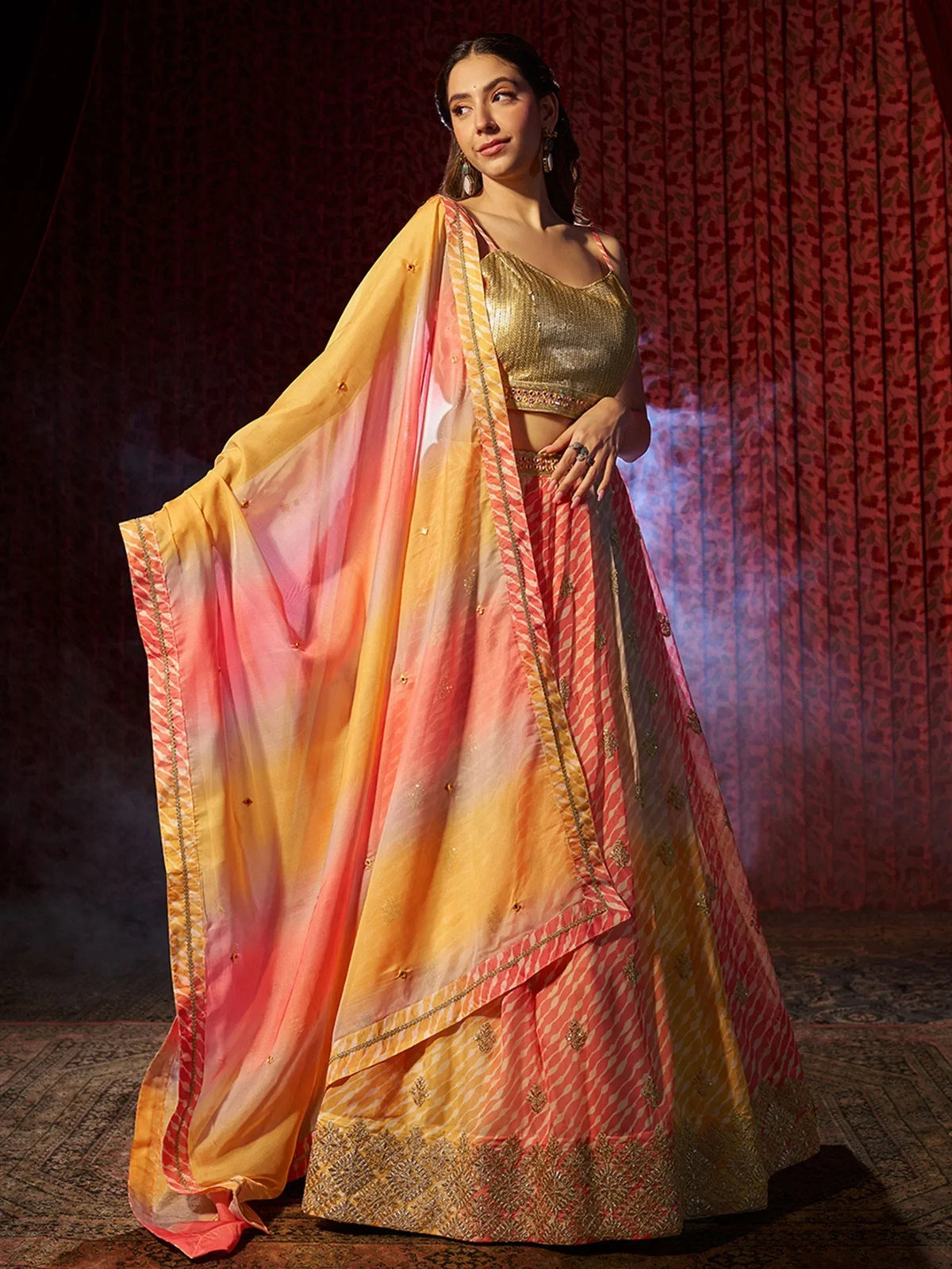 Woman in vibrant peach and gold lehenga choli with ombre dupatta, perfect for Indian ethnic occasions.