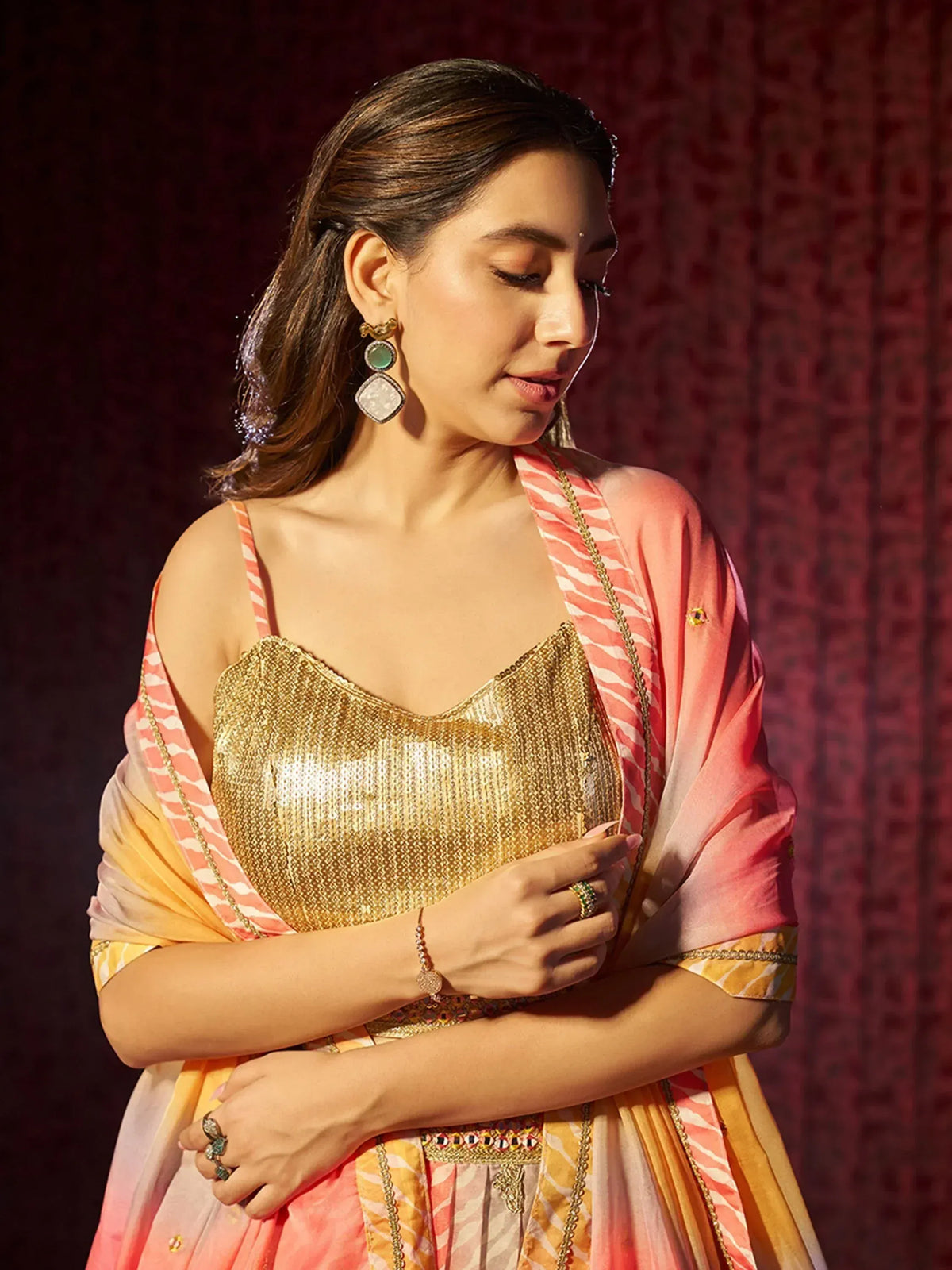Woman in golden sequin lehenga choli with pink and yellow dupatta, ethnic Indian wear