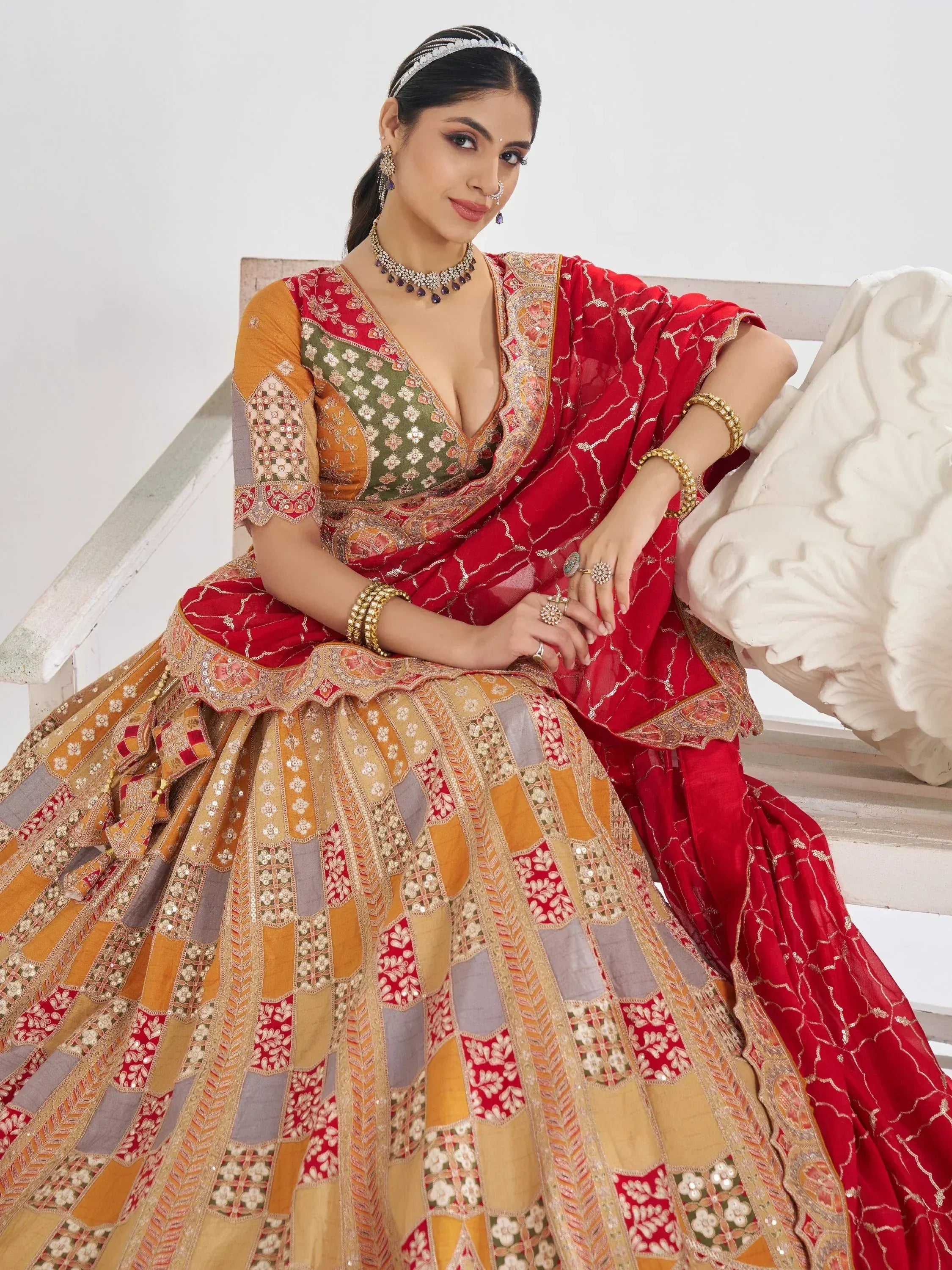 Woman in vibrant red and gold embroidered lehenga choli with floral patterns, traditional Indian ethnic wear