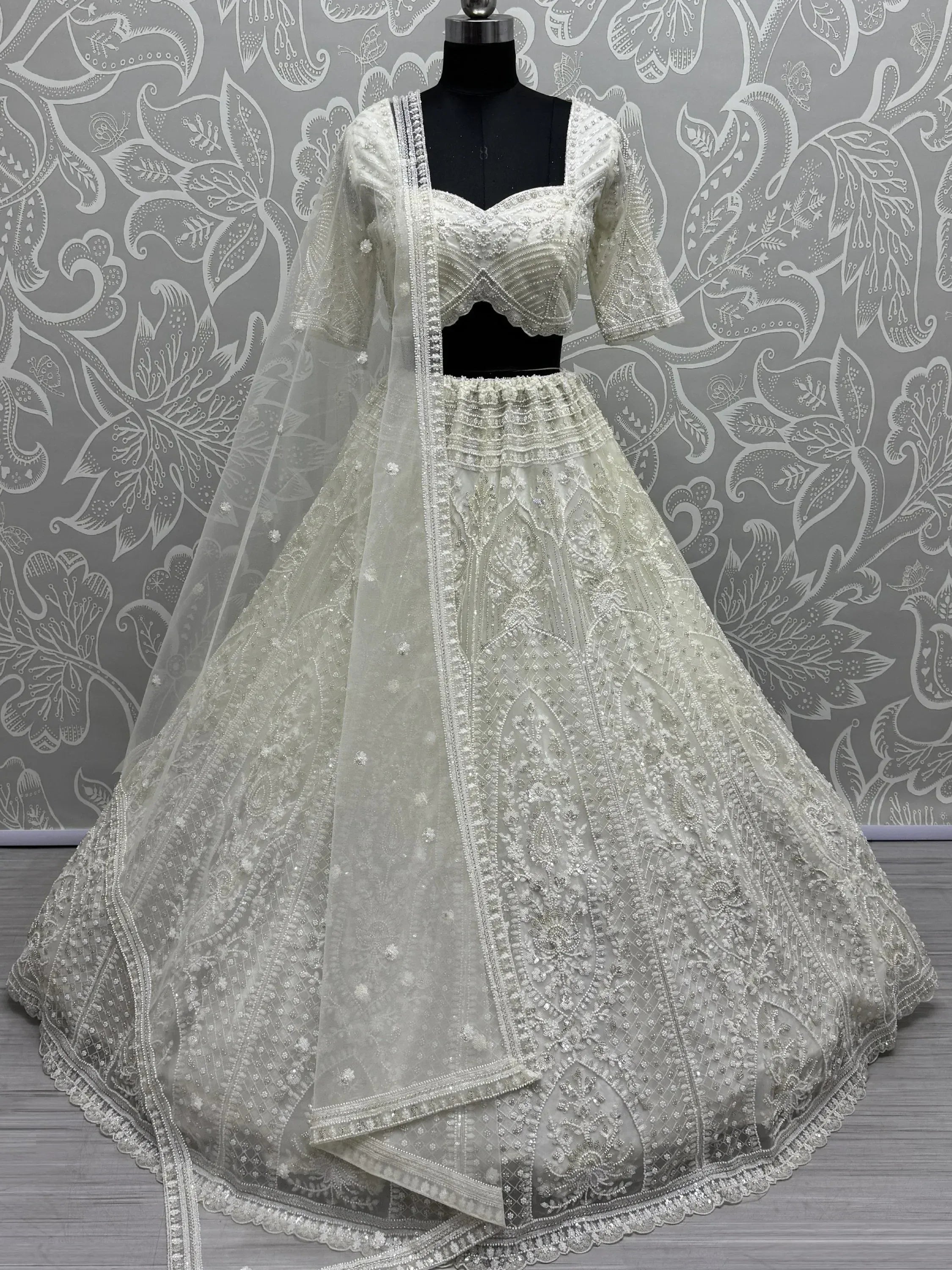 Elegant white embroidered lehenga choli with sheer dupatta, perfect for Indian weddings and festive occasions.