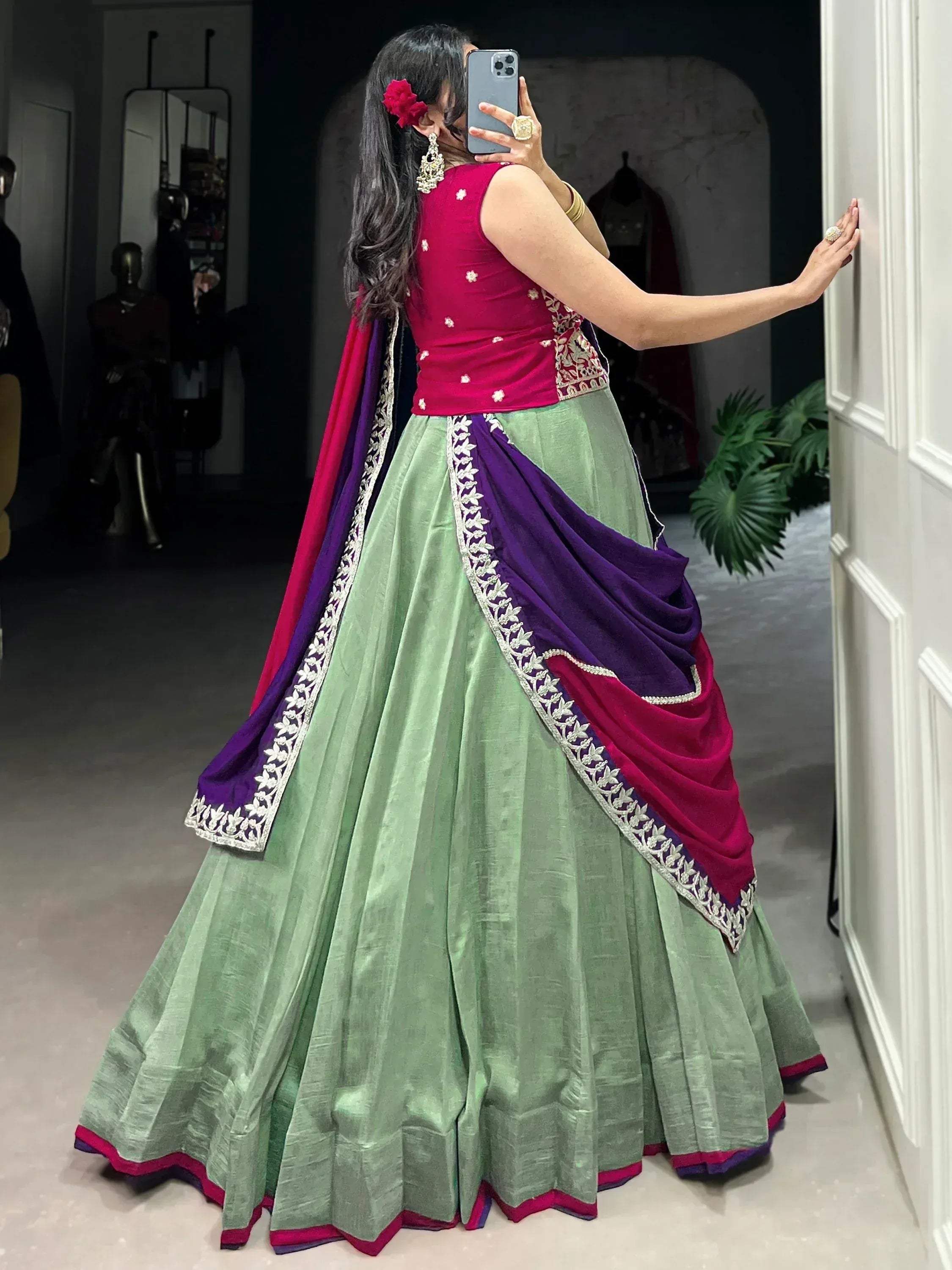 Woman in green lehenga with pink and purple dupatta, floral embroidery, ethnic Indian wear