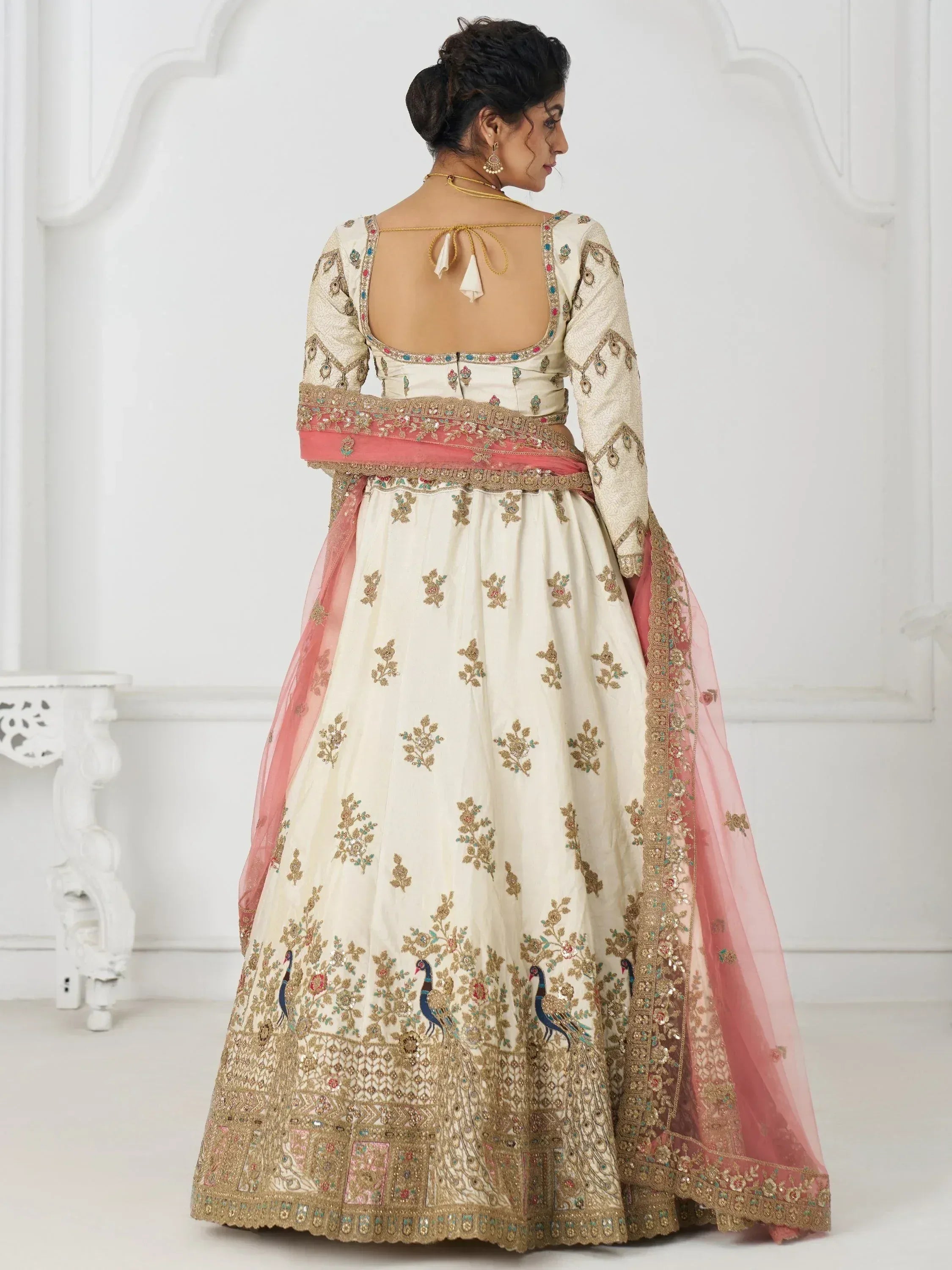 Cream lehenga choli with peacock embroidery, pink dupatta, and open back design for Indian ethnic wear