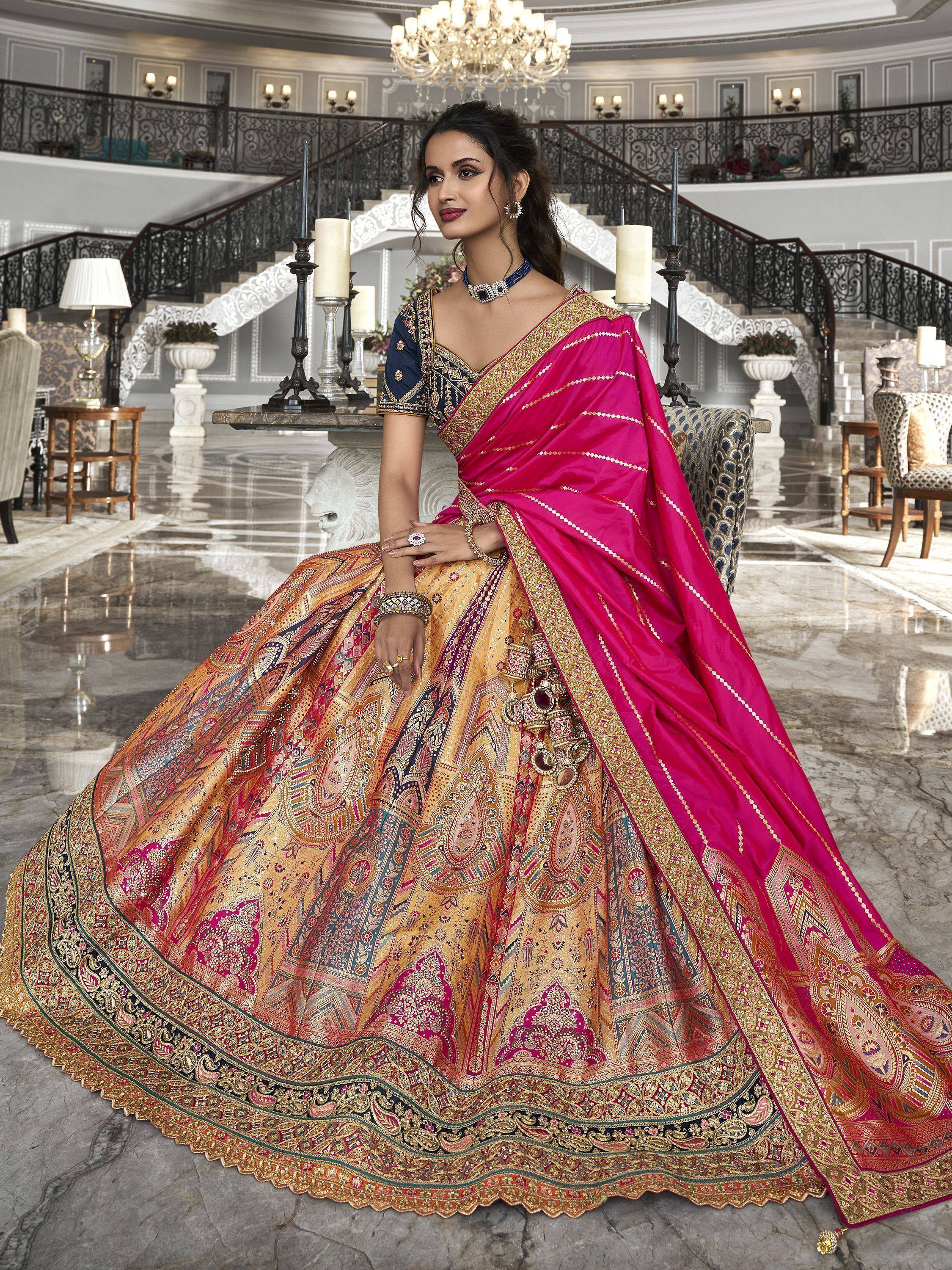 Elegant Indian designer lehenga choli with vibrant pink dupatta, intricate gold embroidery, and paisley print skirt for weddings.