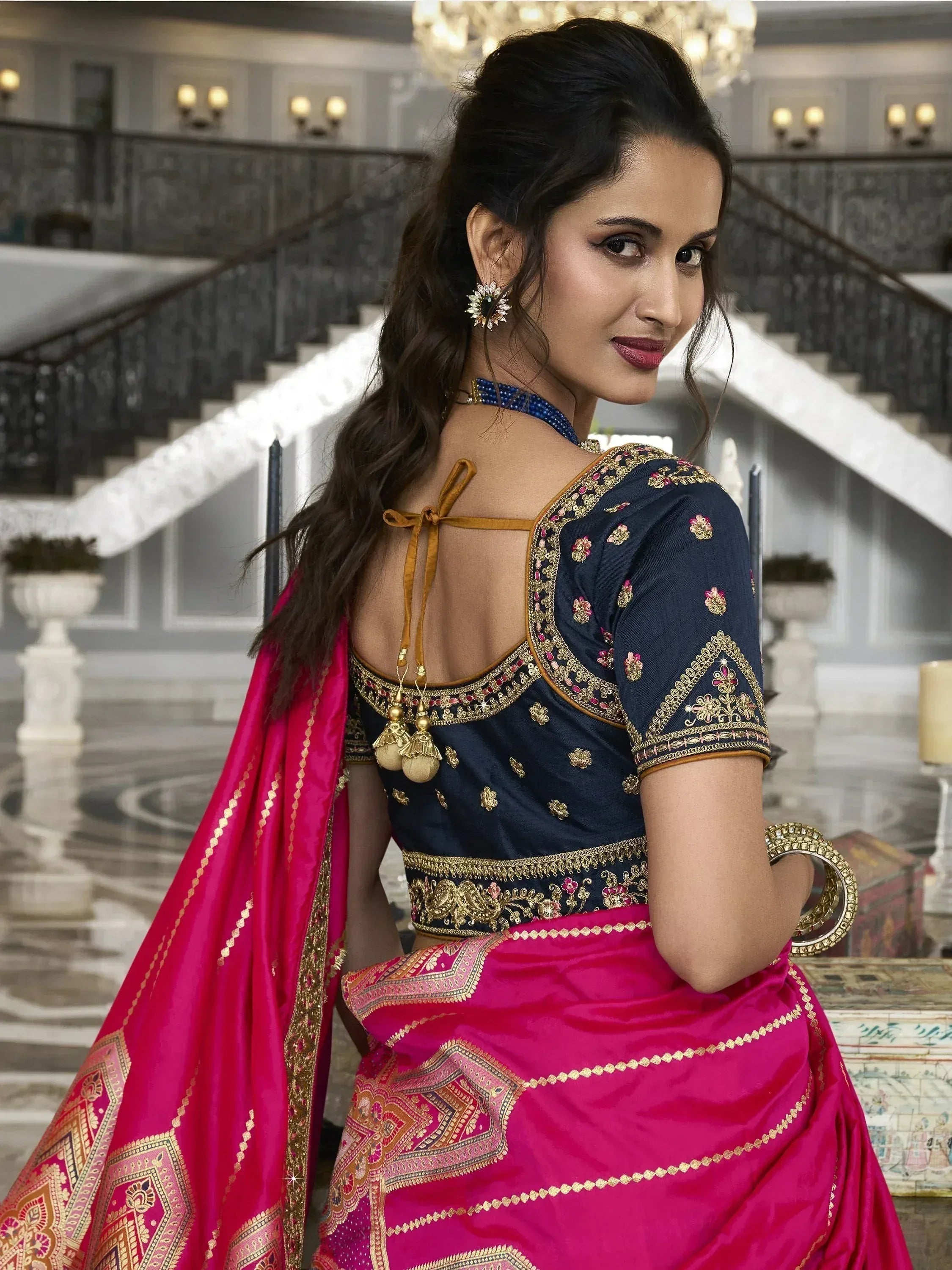 Woman in navy blue embroidered blouse with back tie & pink saree, showcasing Indian ethnic wear