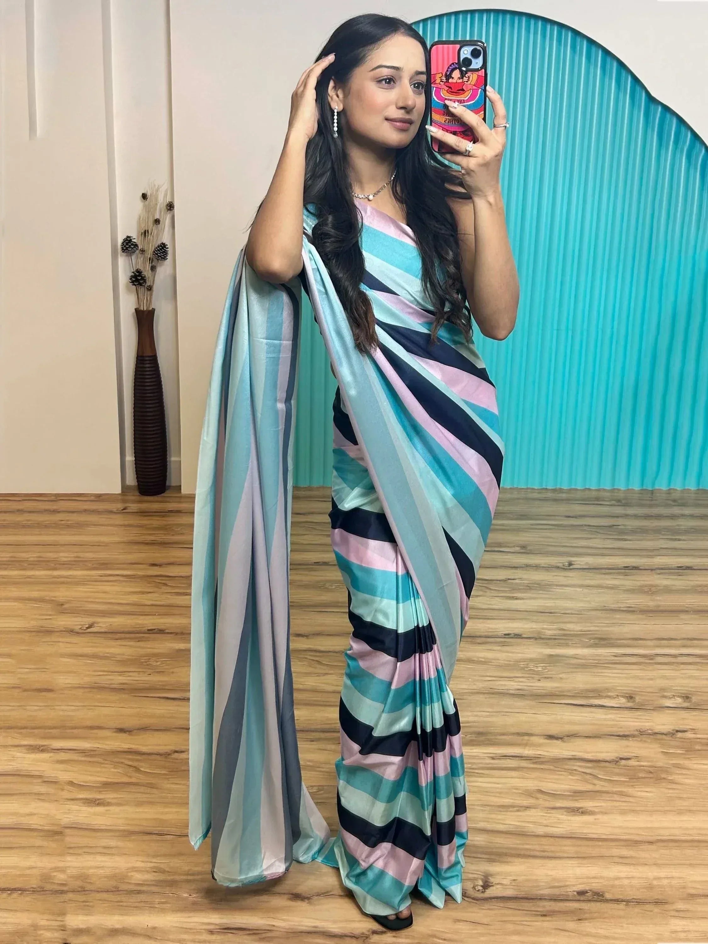 Woman in colorful striped saree, taking mirror selfie with phone, showcasing ethnic wear design