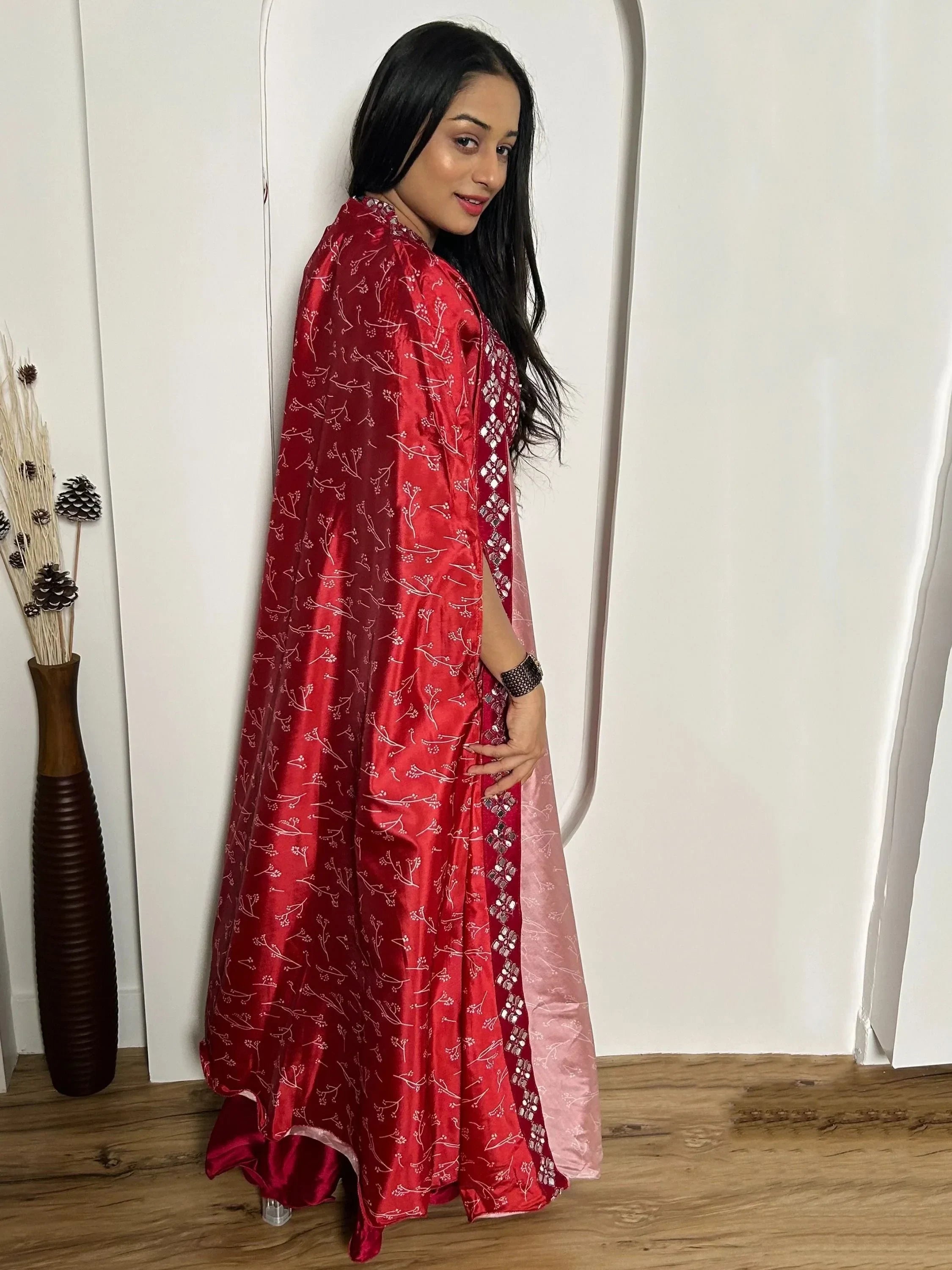 Woman in red and pink Indian ethnic gown with embroidered patterns, standing indoors