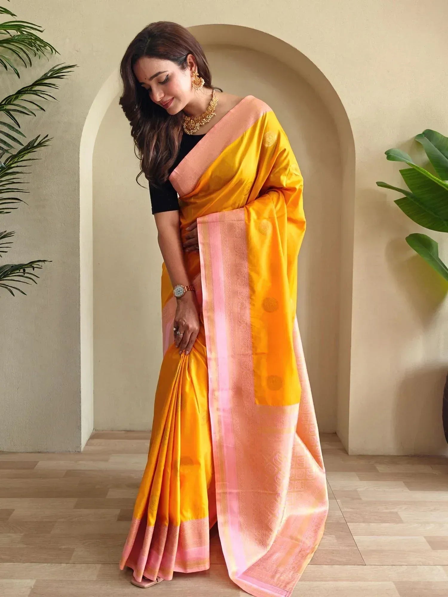Woman in vibrant yellow and pink designer saree with gold jewelry, perfect for ethnic occasions