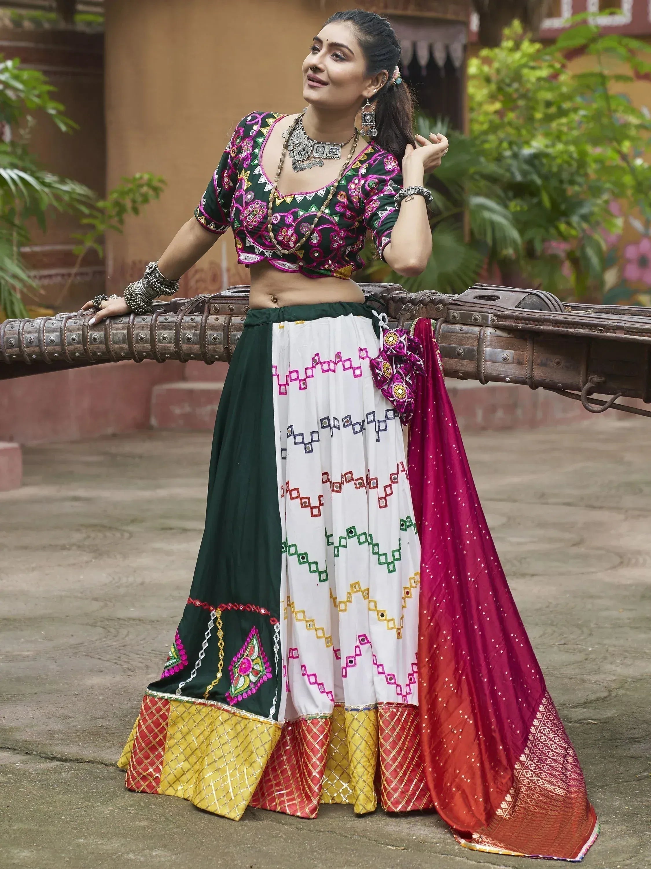 Woman in vibrant green and white embroidered lehenga choli with mirror work, paired with a red dupatta, showcasing traditional Indian ethnic wear.