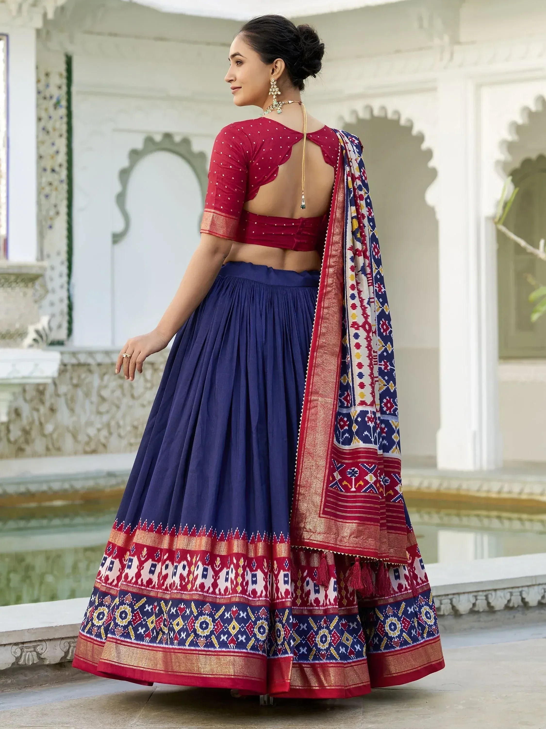 Red and navy blue designer lehenga choli with intricate ikat print and gold border, perfect for Indian ethnic wear.