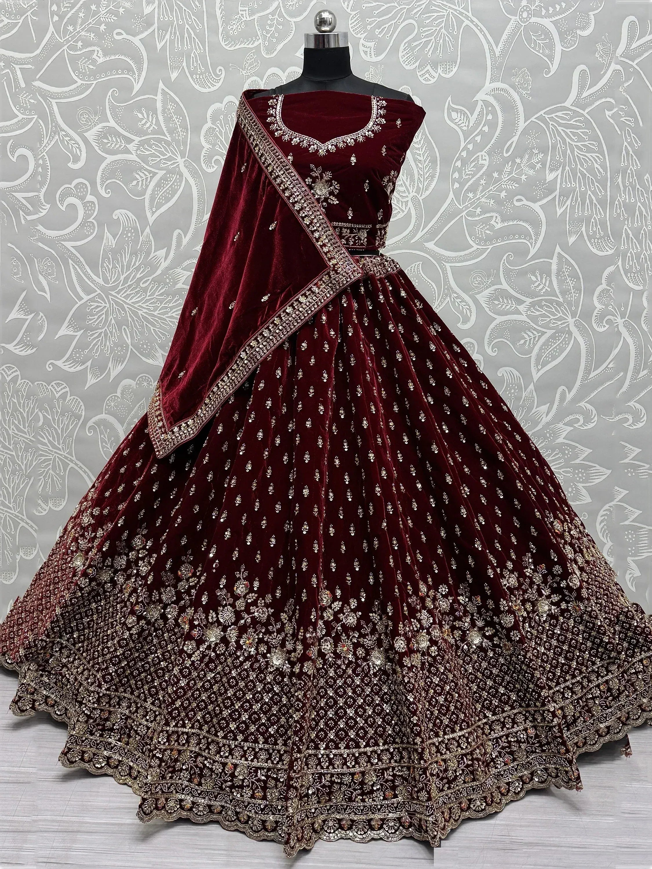 Burgundy velvet lehenga choli with heavy gold embroidery and floral motifs, perfect for Indian weddings.