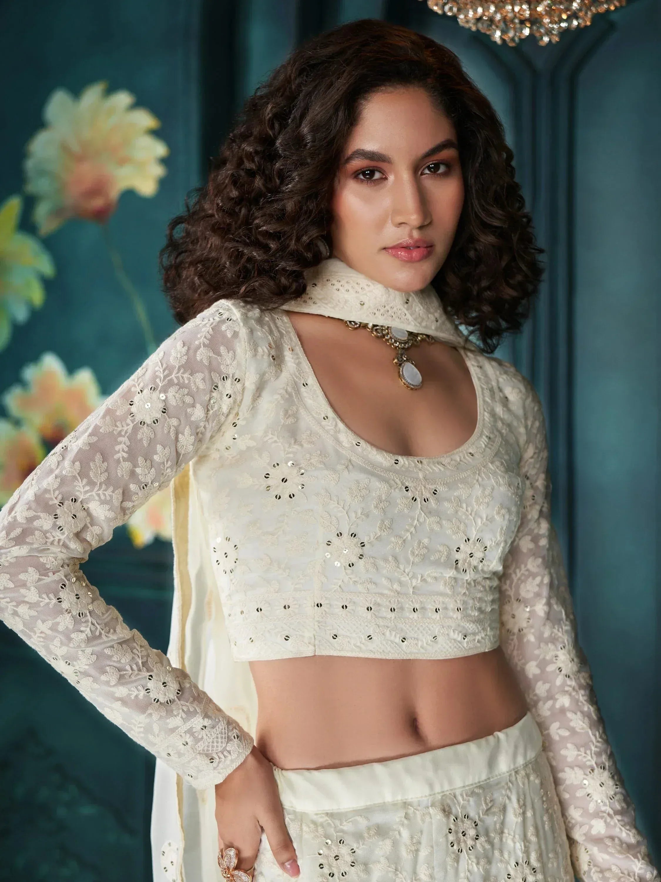 Elegant white embroidered lehenga choli with sheer sleeves and mirror work, perfect for Indian ethnic occasions.