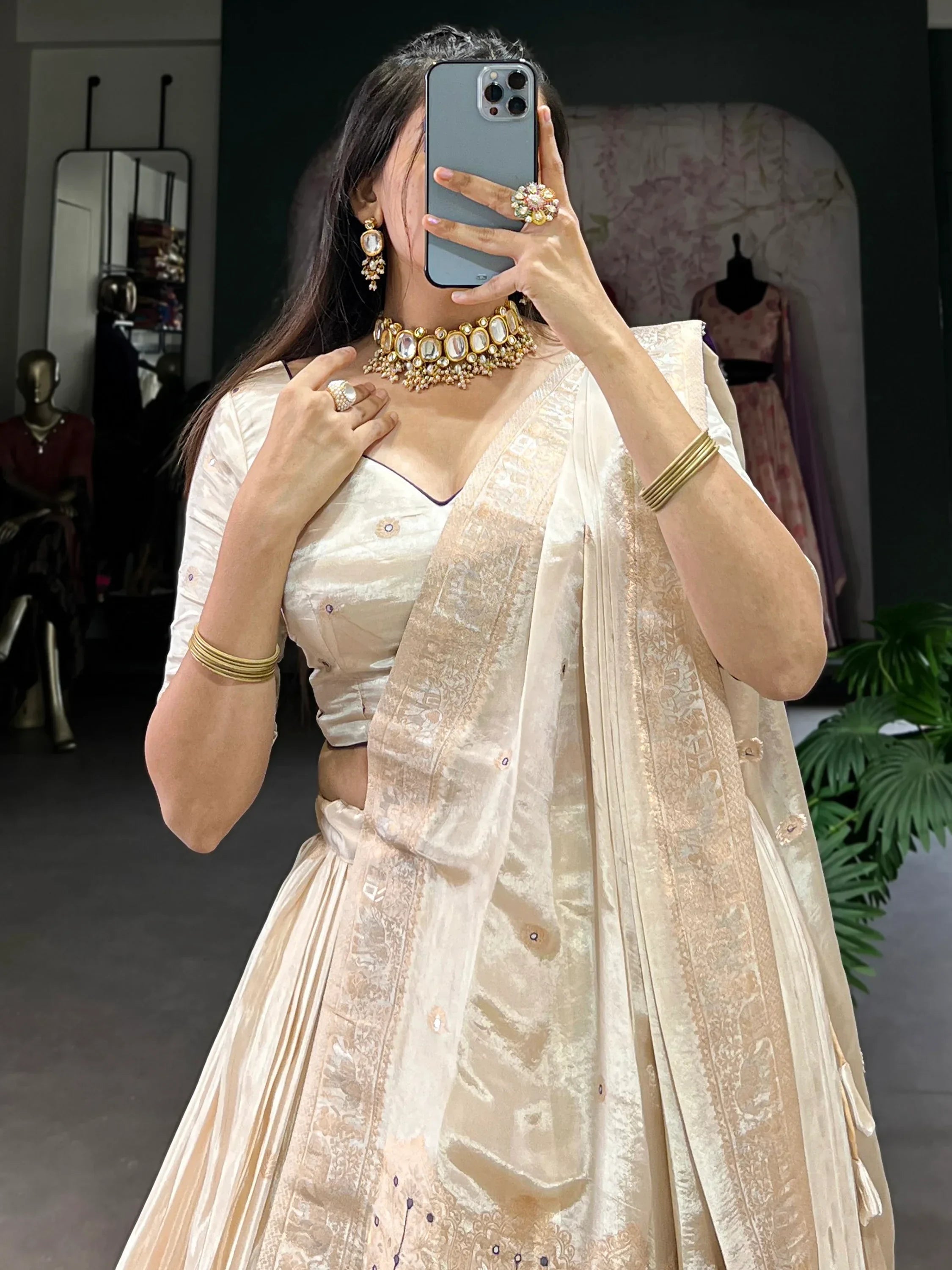Elegant cream lehenga choli with gold embroidery, paired with traditional jewelry for Indian ethnic wear