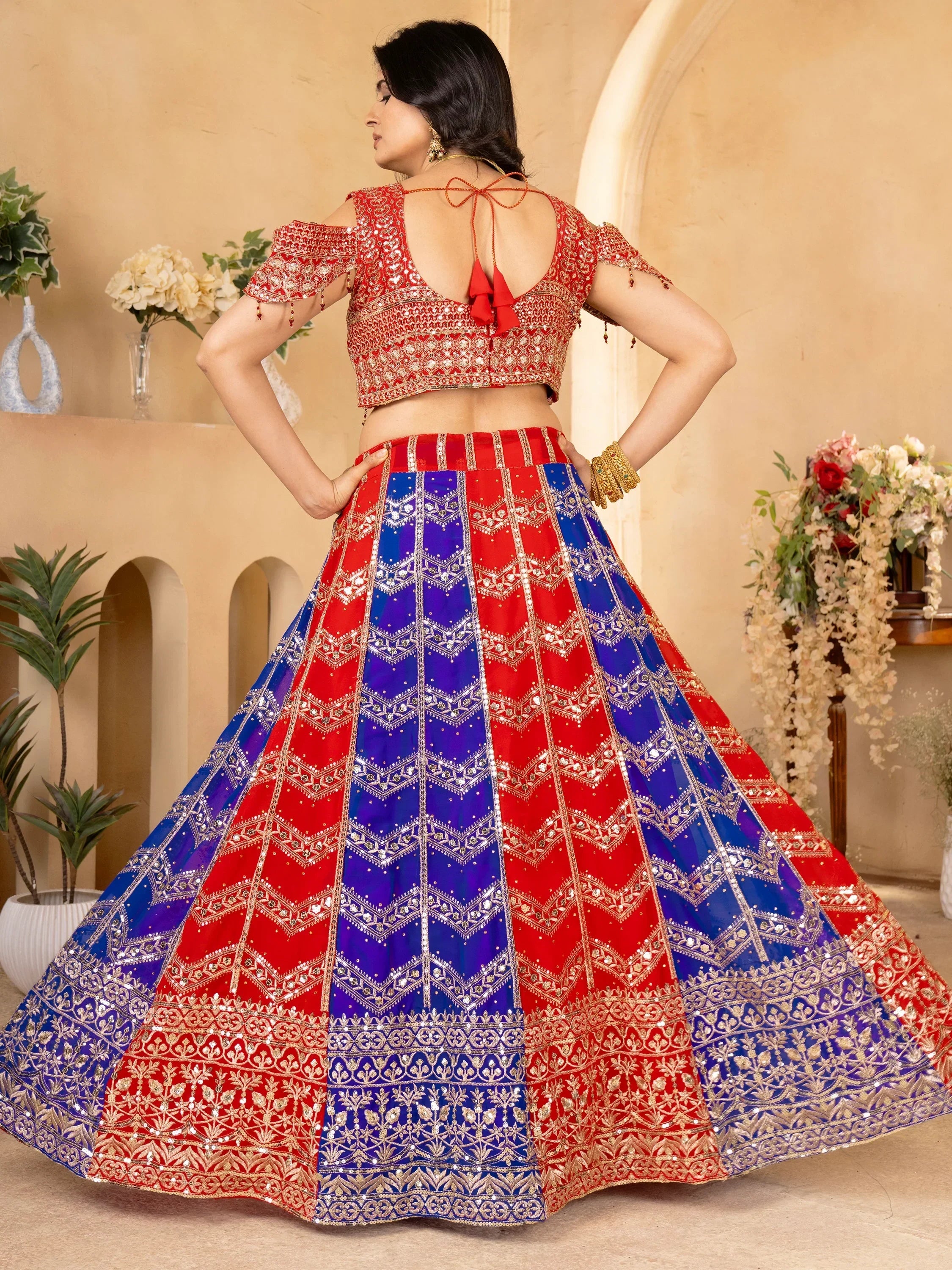 Red and blue embroidered lehenga choli with open back blouse, perfect for Indian weddings and festive occasions.