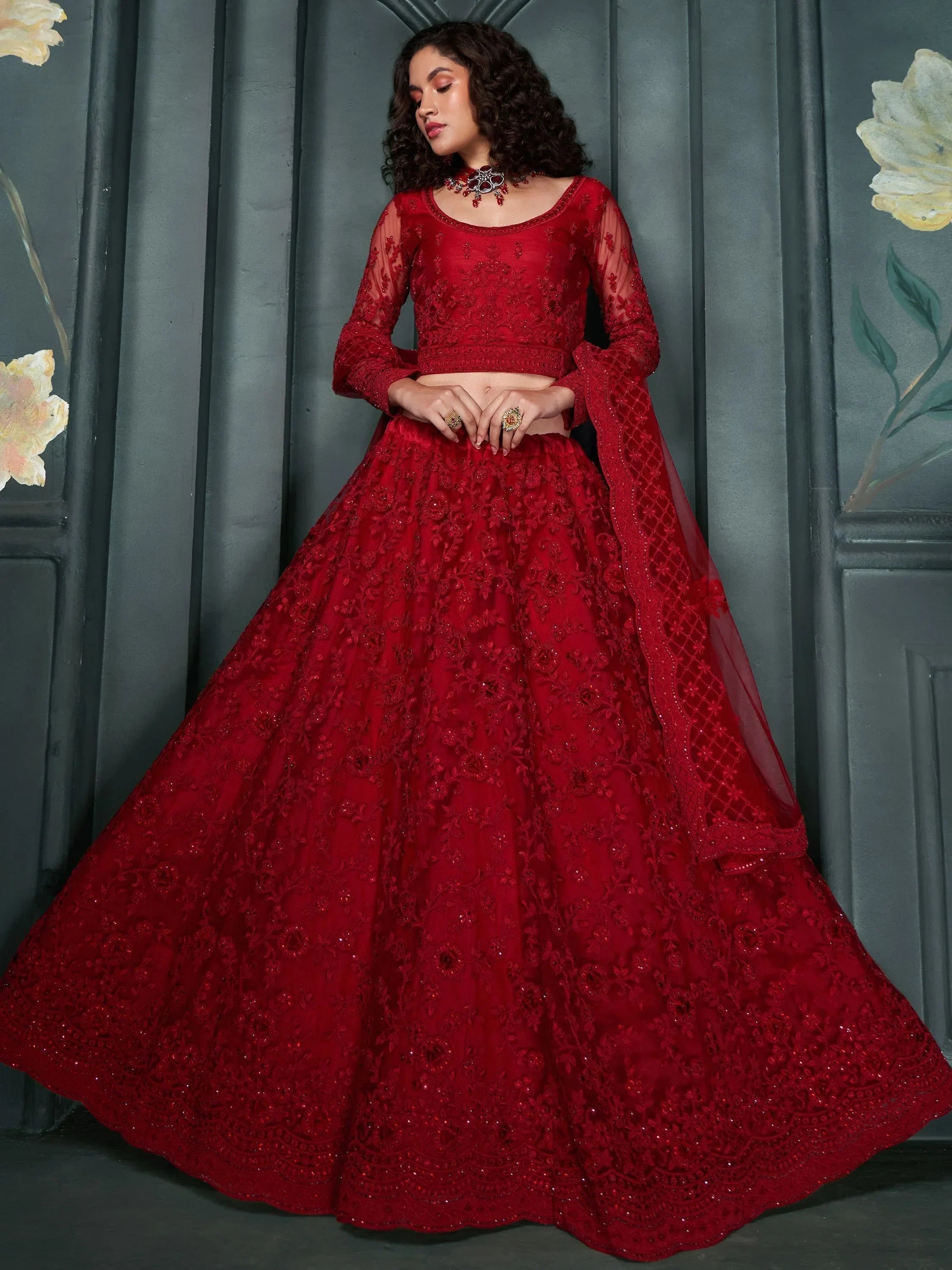 Red embroidered lehenga choli with sheer sleeves and floral detailing, perfect for Indian weddings and festive occasions.