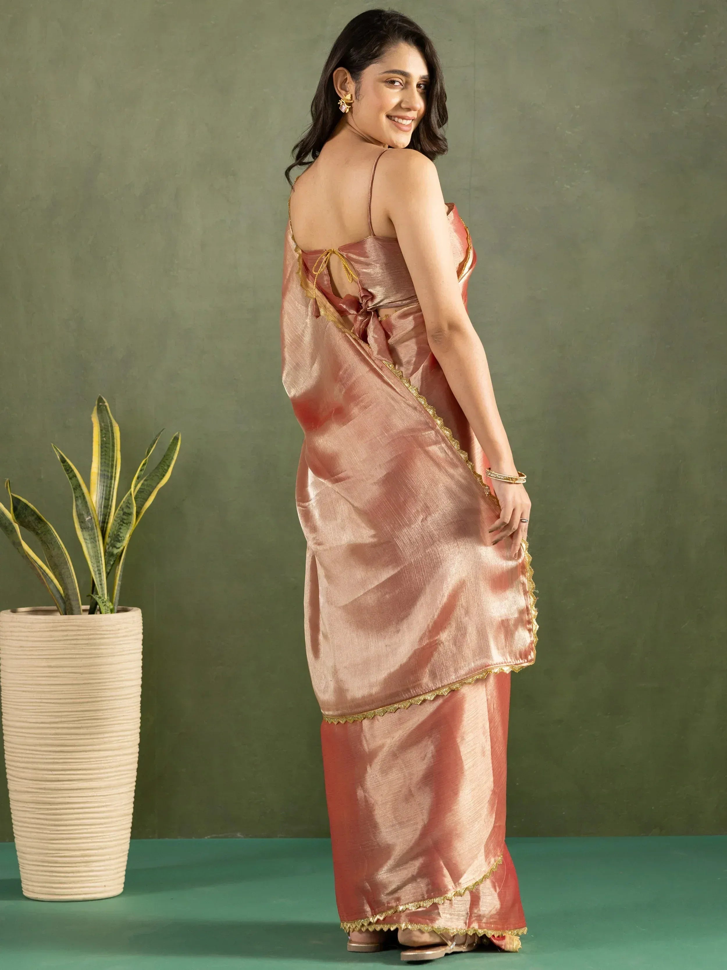 Woman in elegant pink saree with gold trim, backless blouse, perfect for Indian ethnic wear occasions