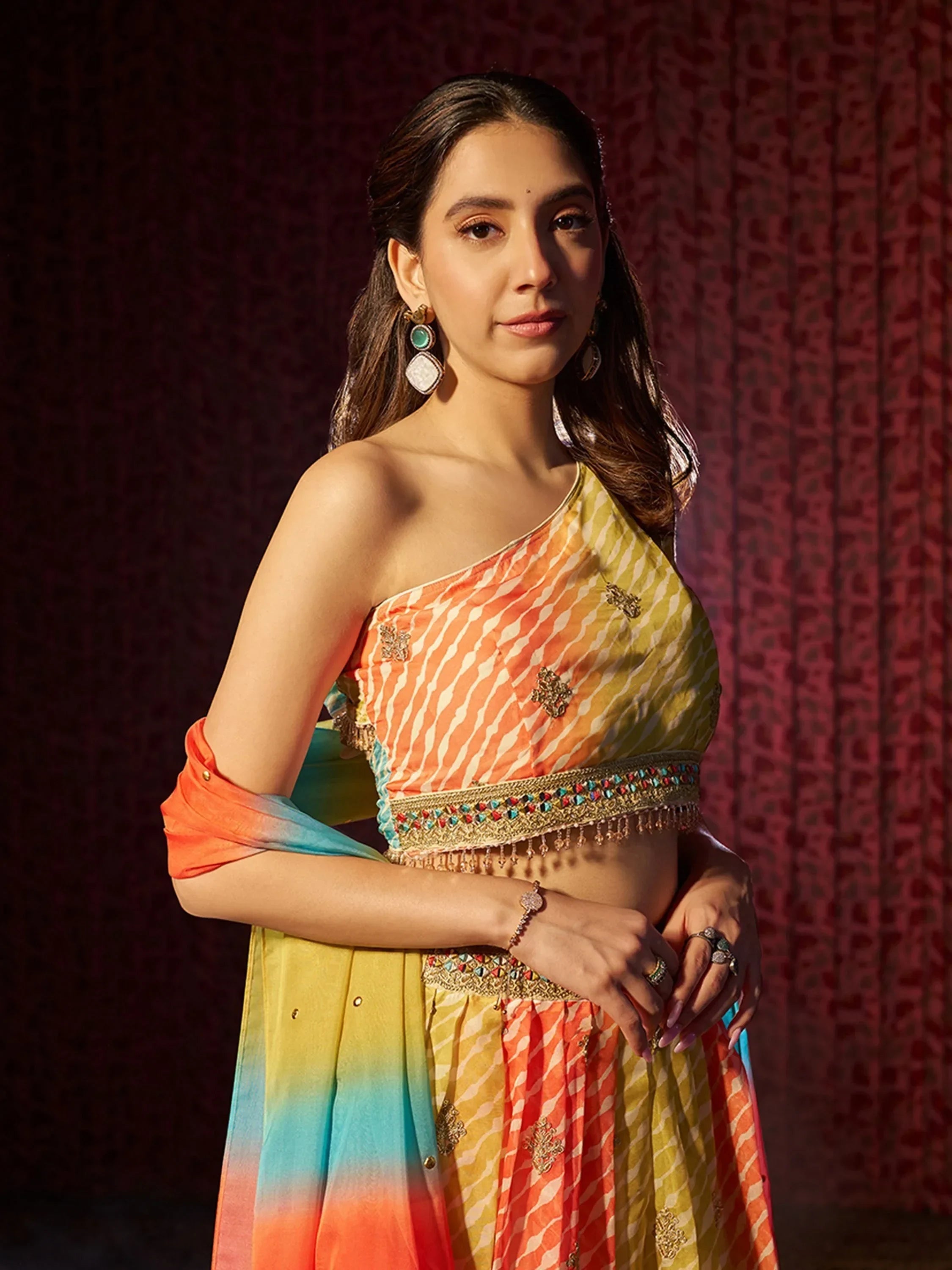 Colorful one-shoulder lehenga choli with embroidered detailing and ombre dupatta, perfect for Indian ethnic occasions.