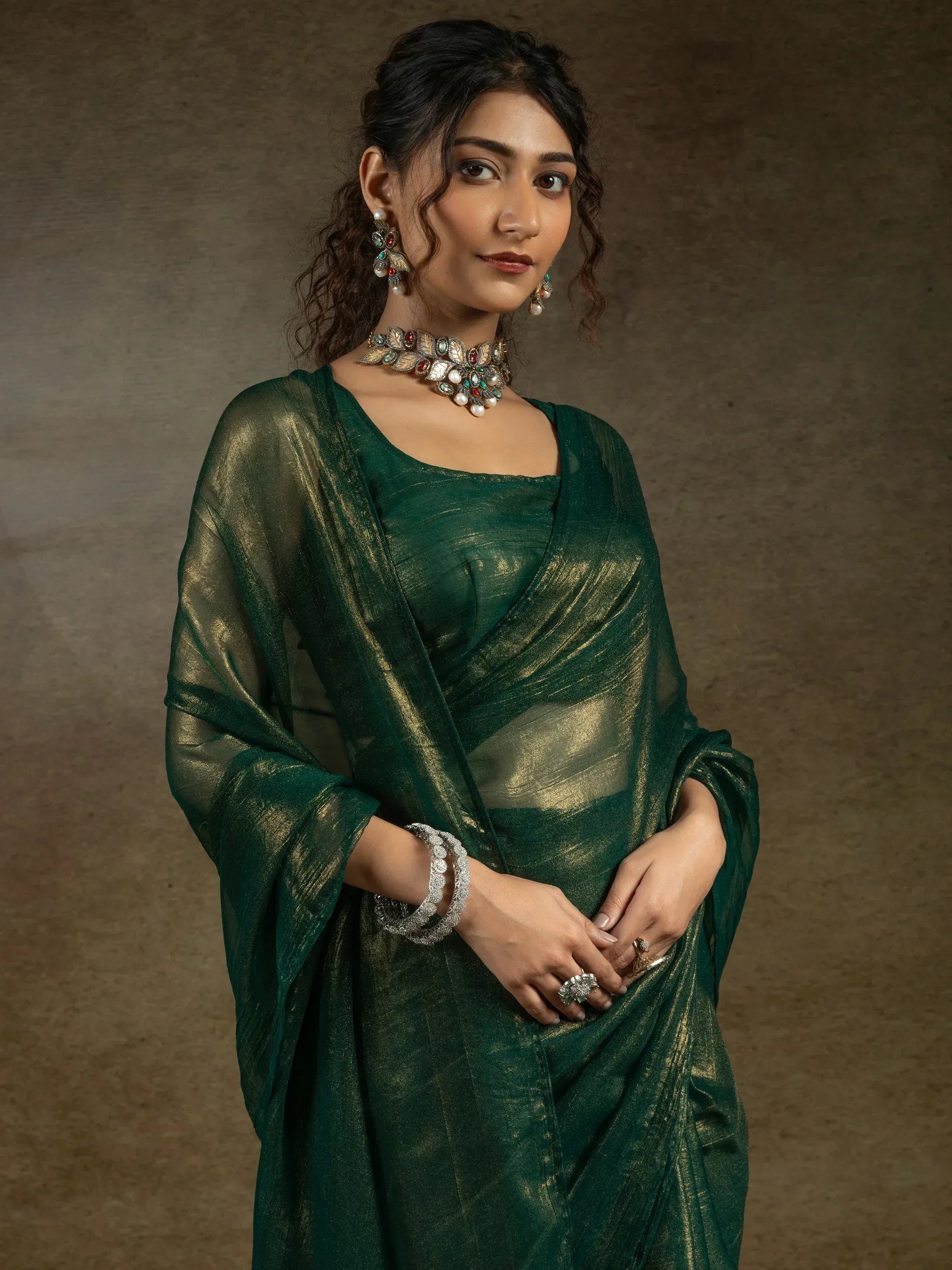 Elegant green saree with gold shimmer, paired with traditional Indian jewelry for festive occasions.