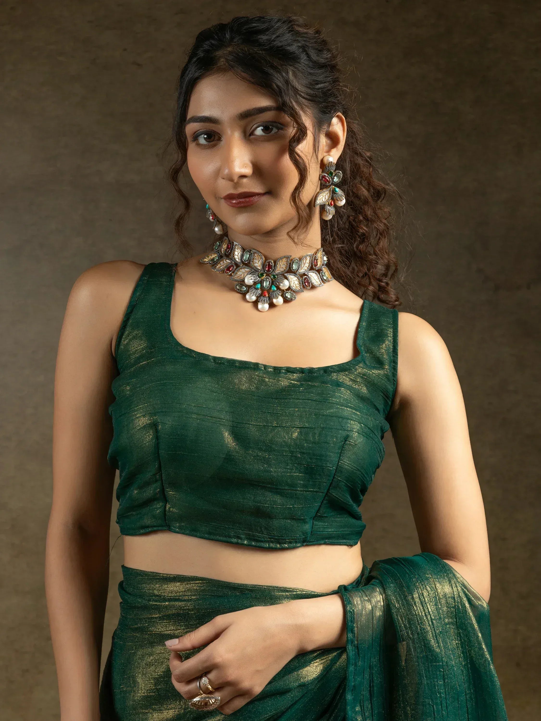 Emerald green saree with shimmering blouse, statement necklace, and floral earrings for Indian ethnic wear