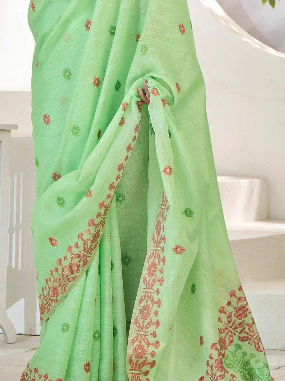 Light green saree with red and green floral print and border, ideal for ethnic wear