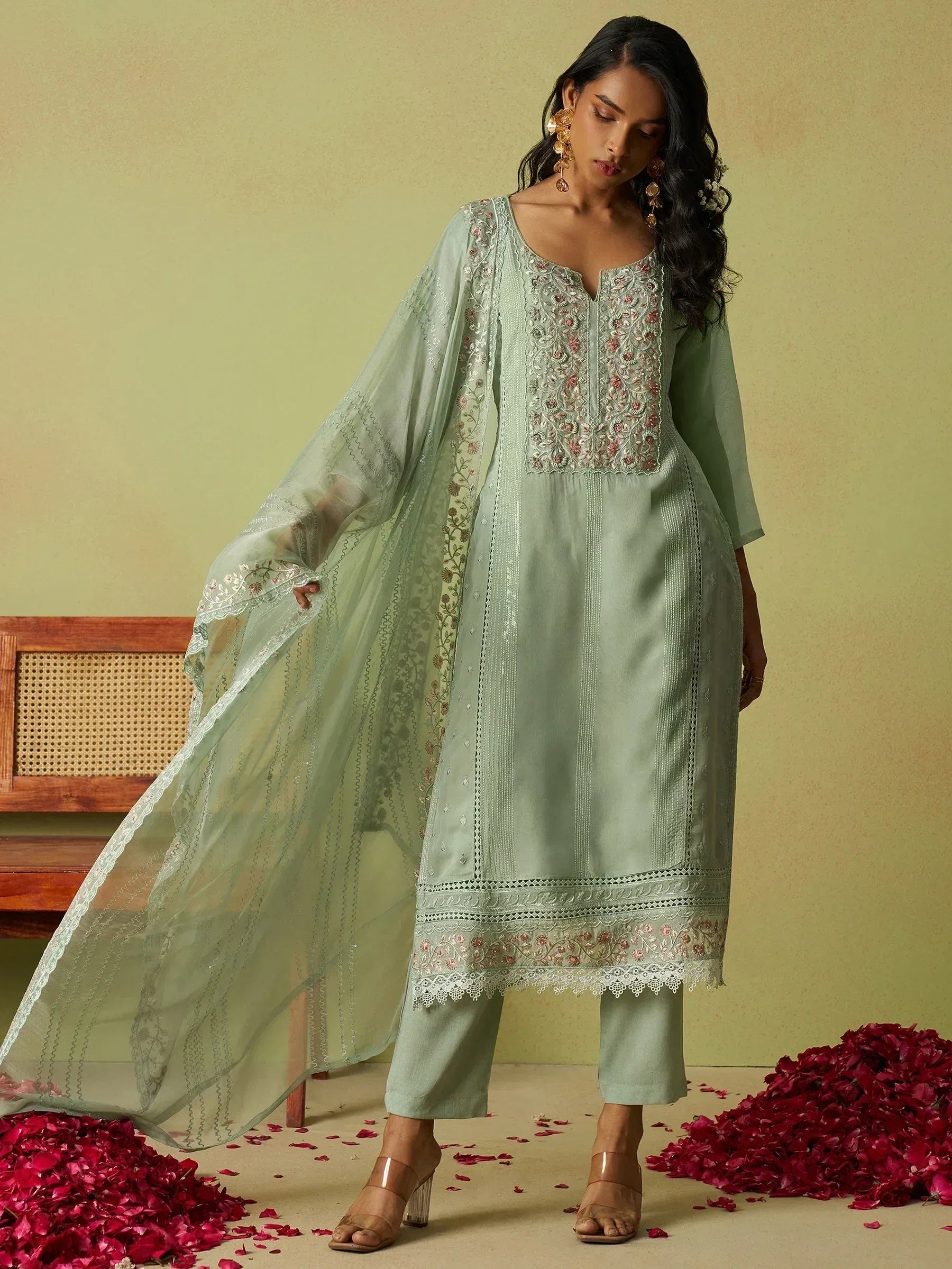 Mint green embroidered salwar kameez with sheer dupatta, floral detailing, and rose petals on floor
