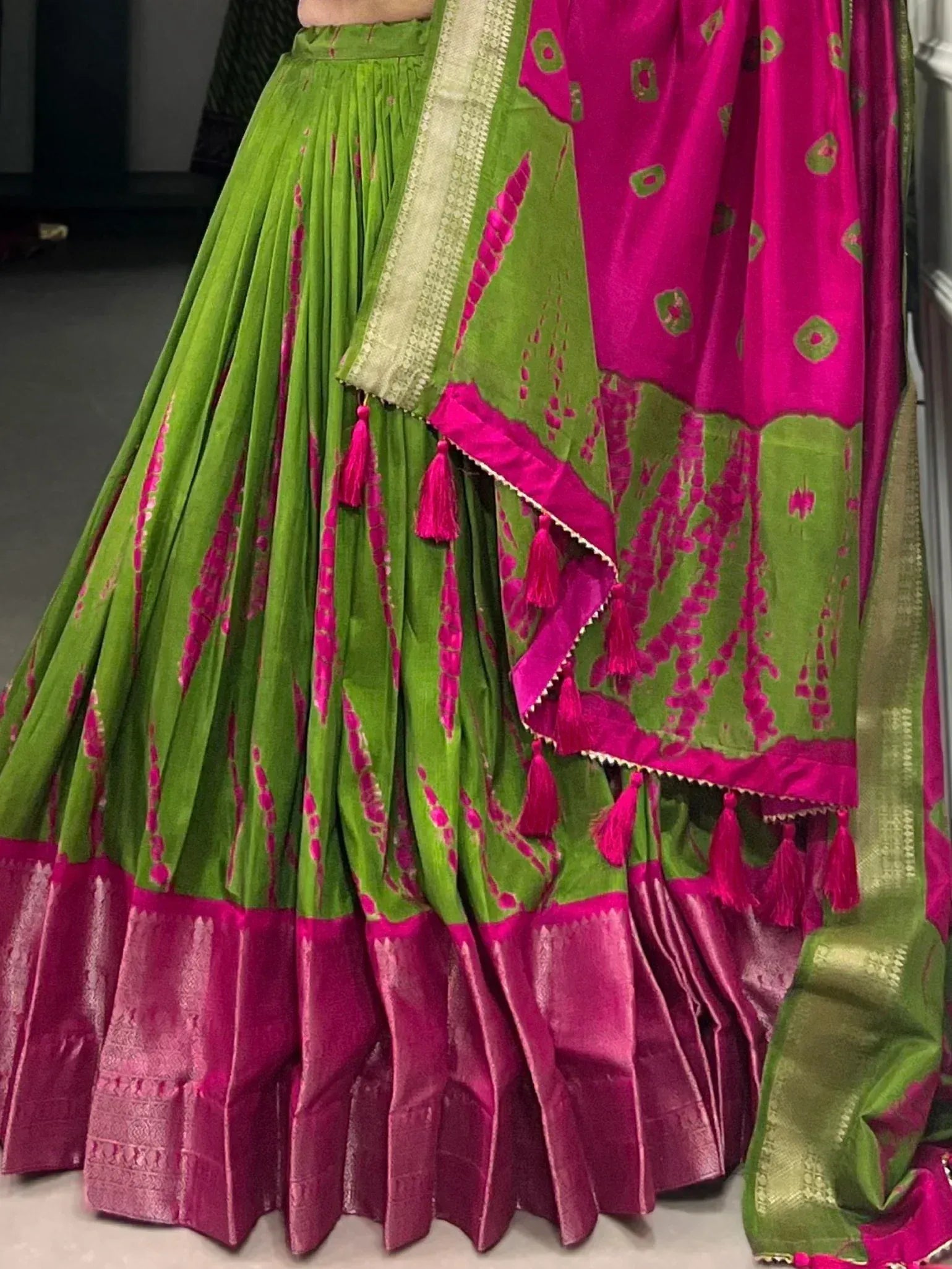 Vibrant green and pink lehenga choli with tassels, perfect for Indian ethnic wear occasions.