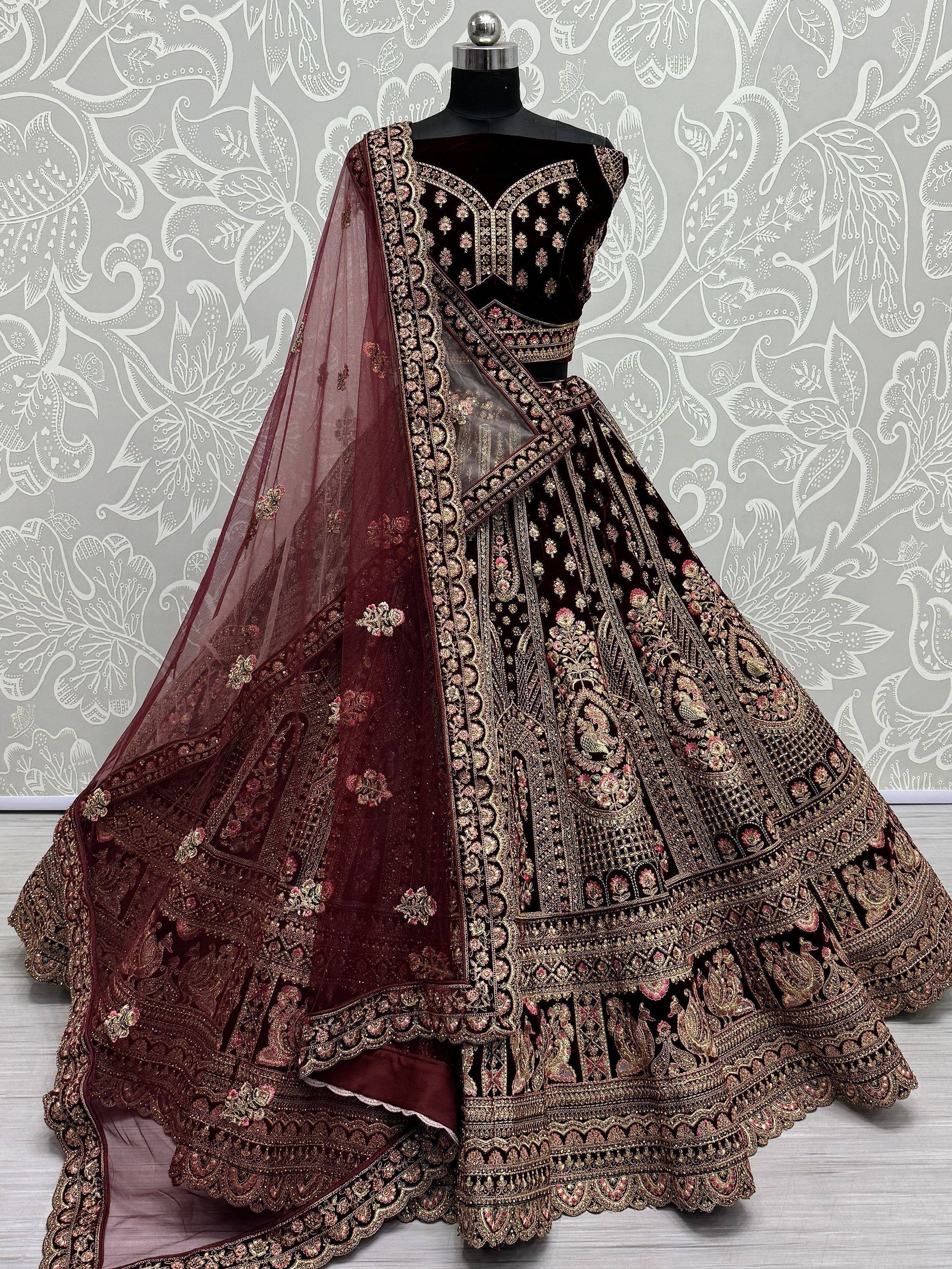 Dark maroon velvet lehenga choli with heavy gold embroidery and sheer dupatta, displayed on mannequin