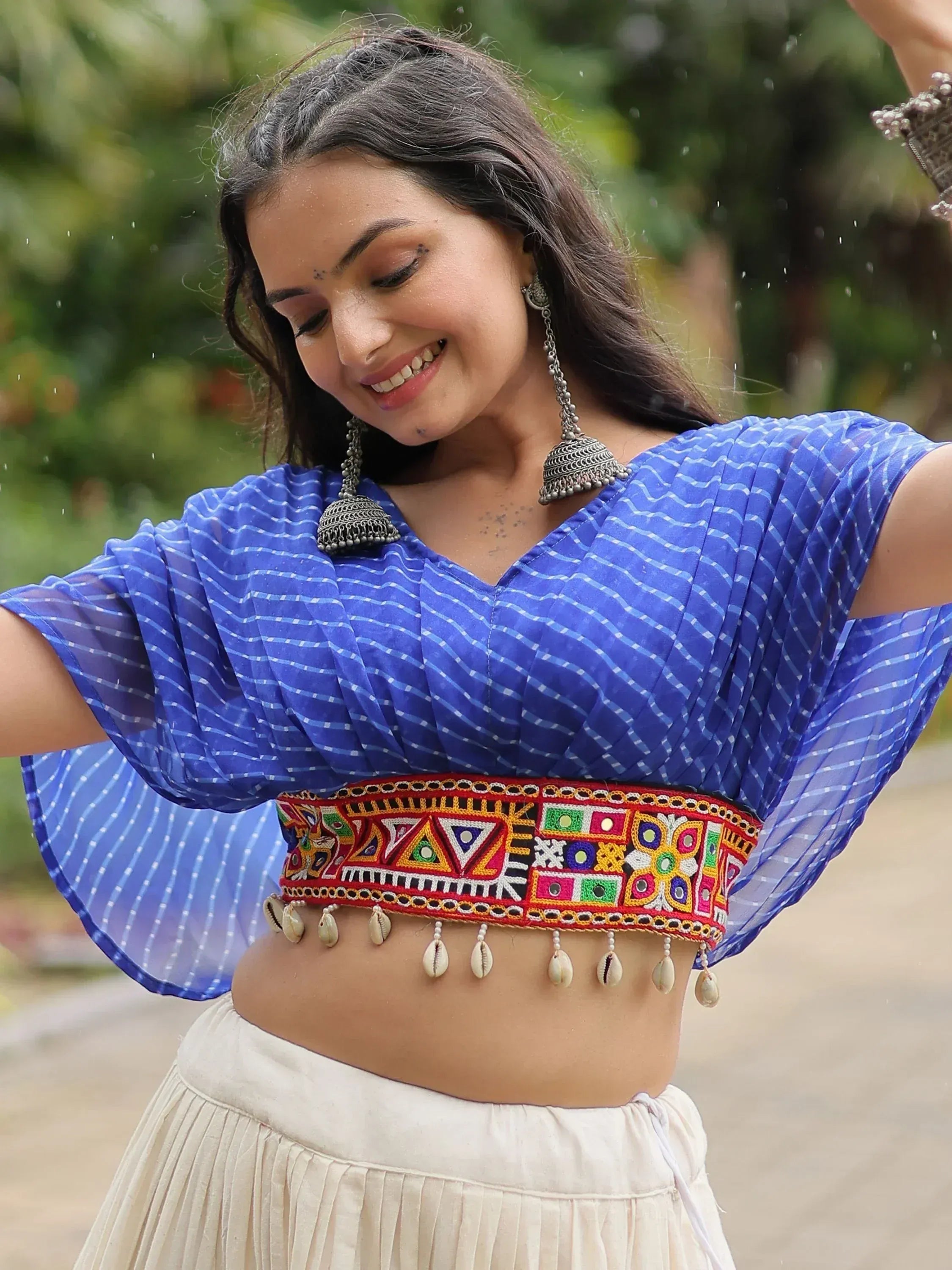 Blue ethnic crop top with mirror work and shell belt, paired with cream skirt, perfect for Indian festive wear